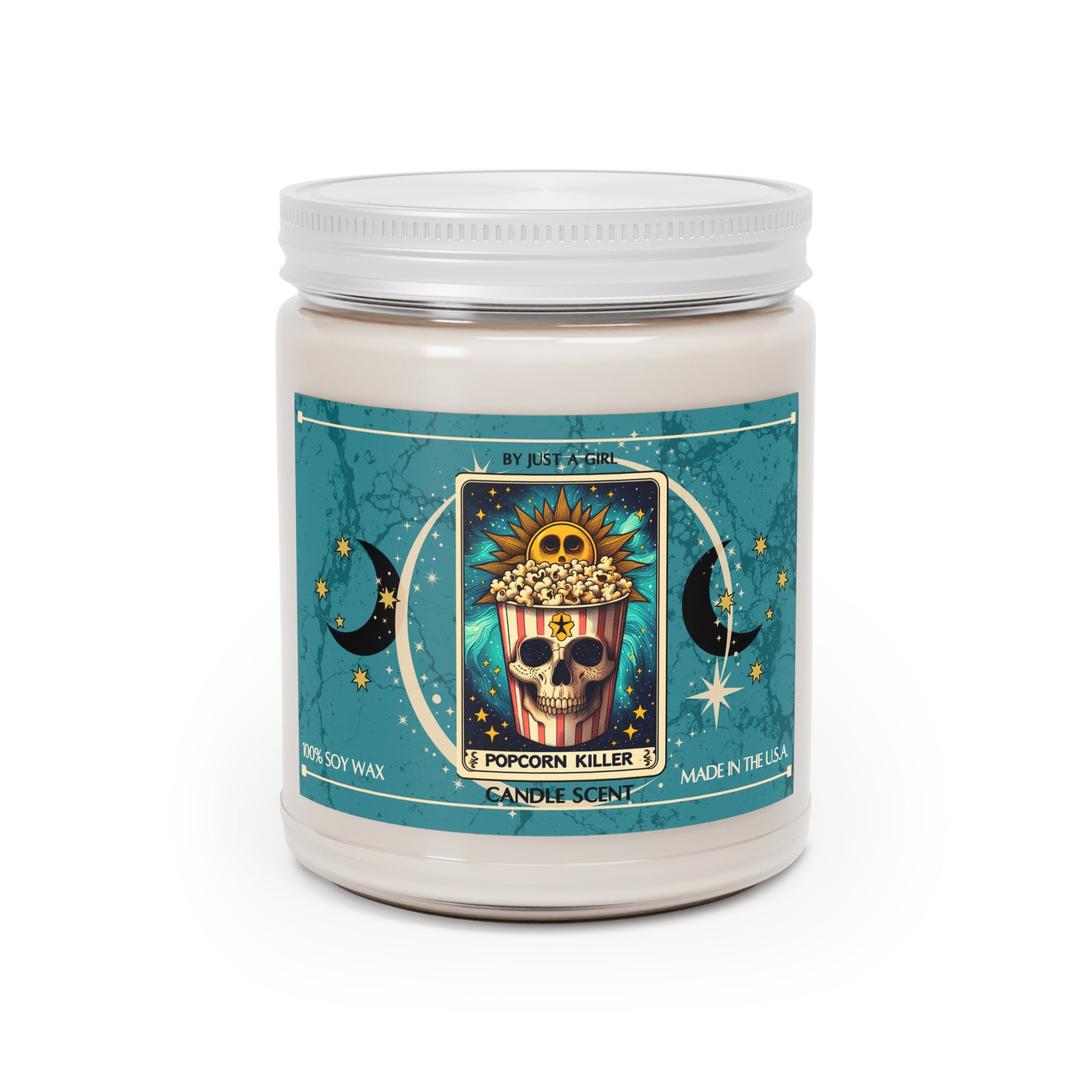 Eine weiße Kerze in einem durchsichtigen Glasgefäß mit weißem Deckel. Das Etikett ist türkisblau mit Mond- und Sternmotiven und zeigt in der Mitte eine goldgerahmte Illustration. Darauf ist ein Popcorn-Eimer abgebildet, dessen unterer Teil ein Totenkopfgesicht zeigt, gefüllt mit Popcorn, und oben eine lachende Sonne. Der Text auf dem Etikett lautet "BY JUST A GIRL".