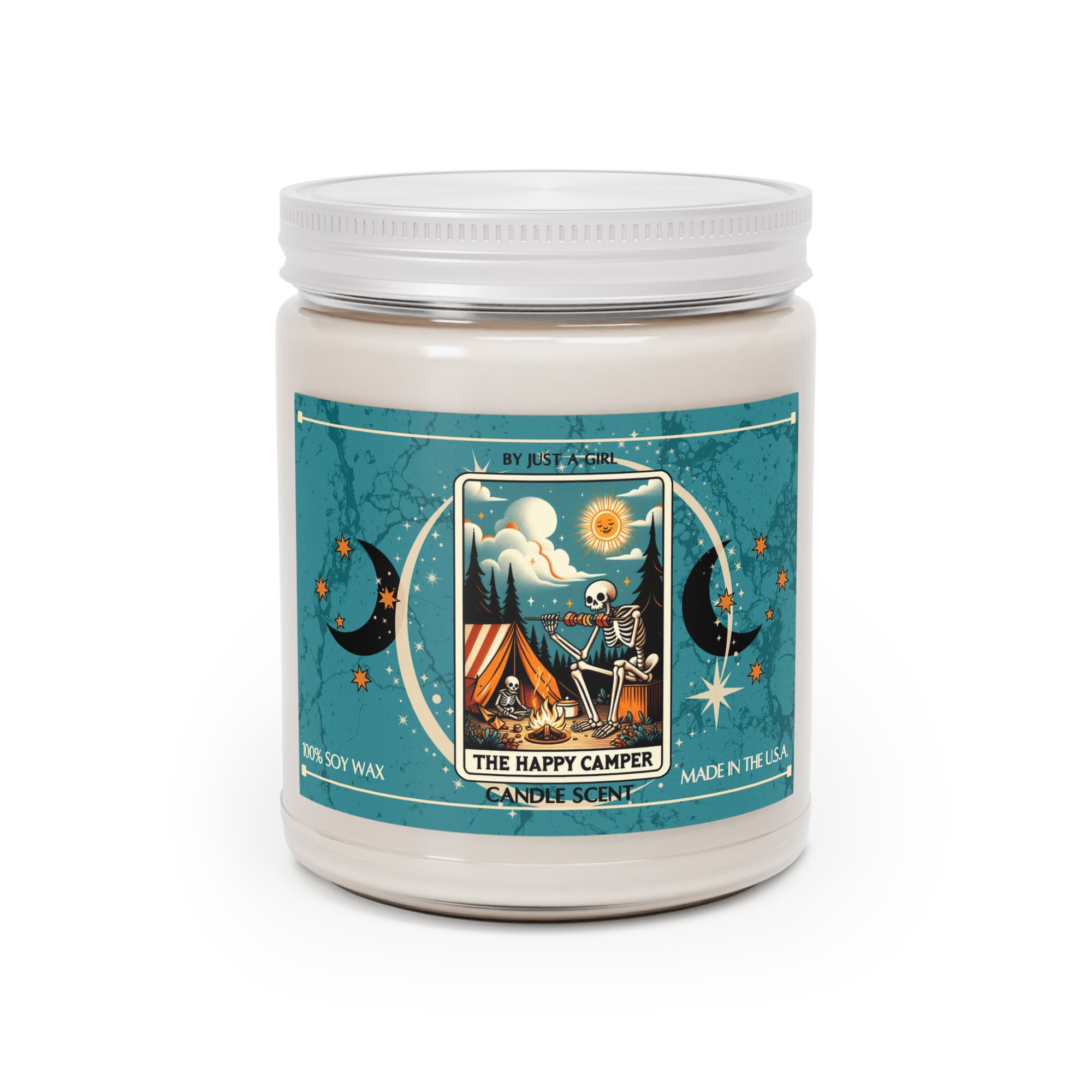 Eine weiße Kerze in einem durchsichtigen Glasgefäß mit weißem Deckel. Das Etikett ist türkisblau mit Mond- und Sternmotiven und zeigt in der Mitte eine goldgerahmte Illustration. Darauf ist ein Skelett zu sehen, das vor einem Zelt an einem Lagerfeuer sitzt und Gitarre spielt, unter einer lachenden Sonne. Über dem Skelett ist ein sternenklarer Nachthimmel mit einem Vollmond und Noten zu sehen. Der Text auf dem Etikett lautet "BY JUST A GIRL".