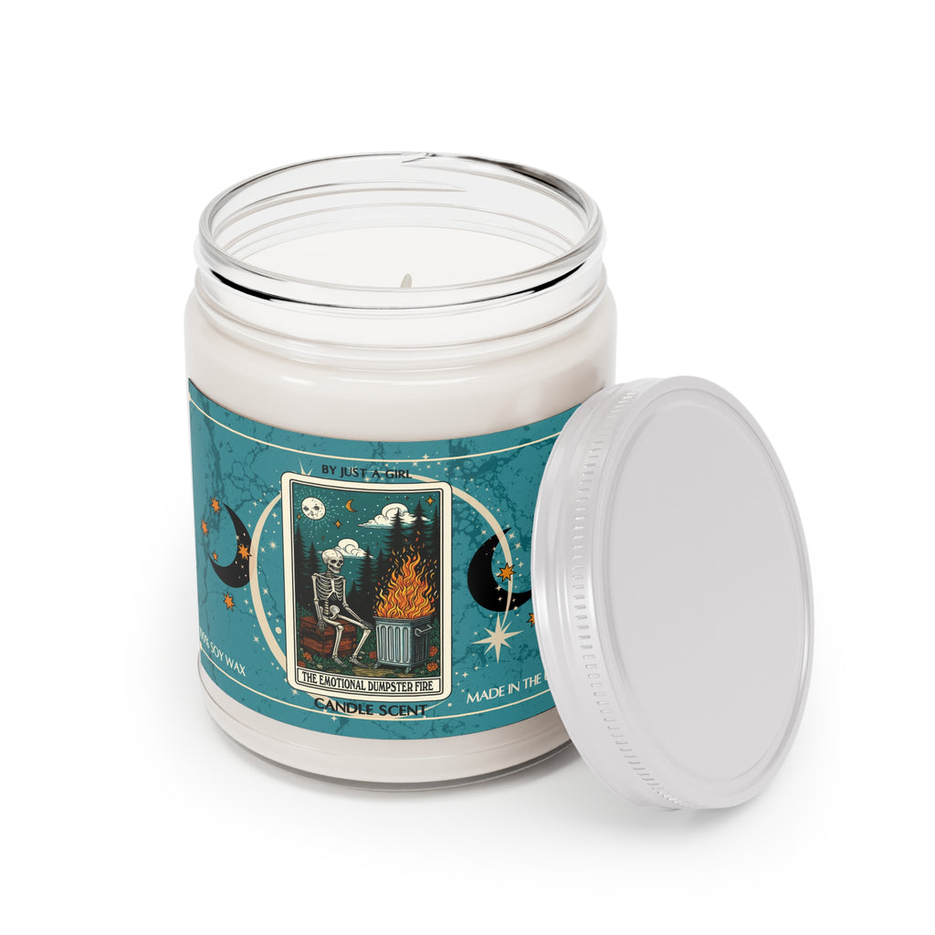 Eine weiße Kerze in einem durchsichtigen Glasgefäß mit weißem Deckel. Das Etikett ist türkisblau mit Mond- und Sternmotiven und zeigt in der Mitte eine goldgerahmte Illustration. Darauf ist ein Skelett zu sehen, das auf einer Bank vor einem brennenden Mülleimer sitzt. Über dem Skelett ist ein sternenklarer Nachthimmel mit einem Mond zu sehen. Der Text auf dem Etikett lautet "BY JUST A GIRL".