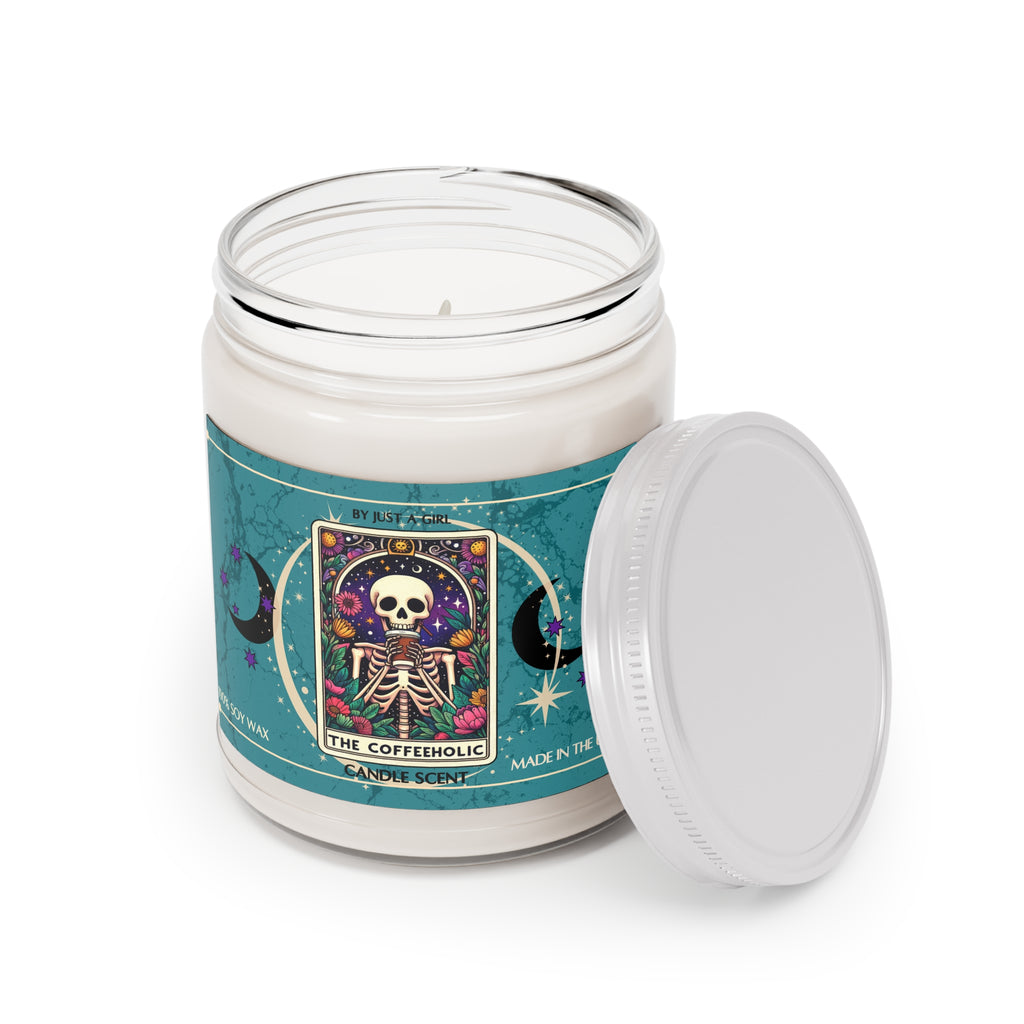 Eine weiße Kerze in einem durchsichtigen Glasgefäß mit weißem Deckel. Das Etikett ist türkisblau mit Mond- und Sternmotiven und zeigt in der Mitte eine goldgerahmte Illustration. Darauf ist ein sitzendes Skelett zu sehen, das eine Tasse Kaffee trinkt, umgeben von bunten Blumen und unter einem sternenklaren Nachthimmel mit einem Halbmond. Der Text auf dem Etikett lautet "BY JUST A GIRL".