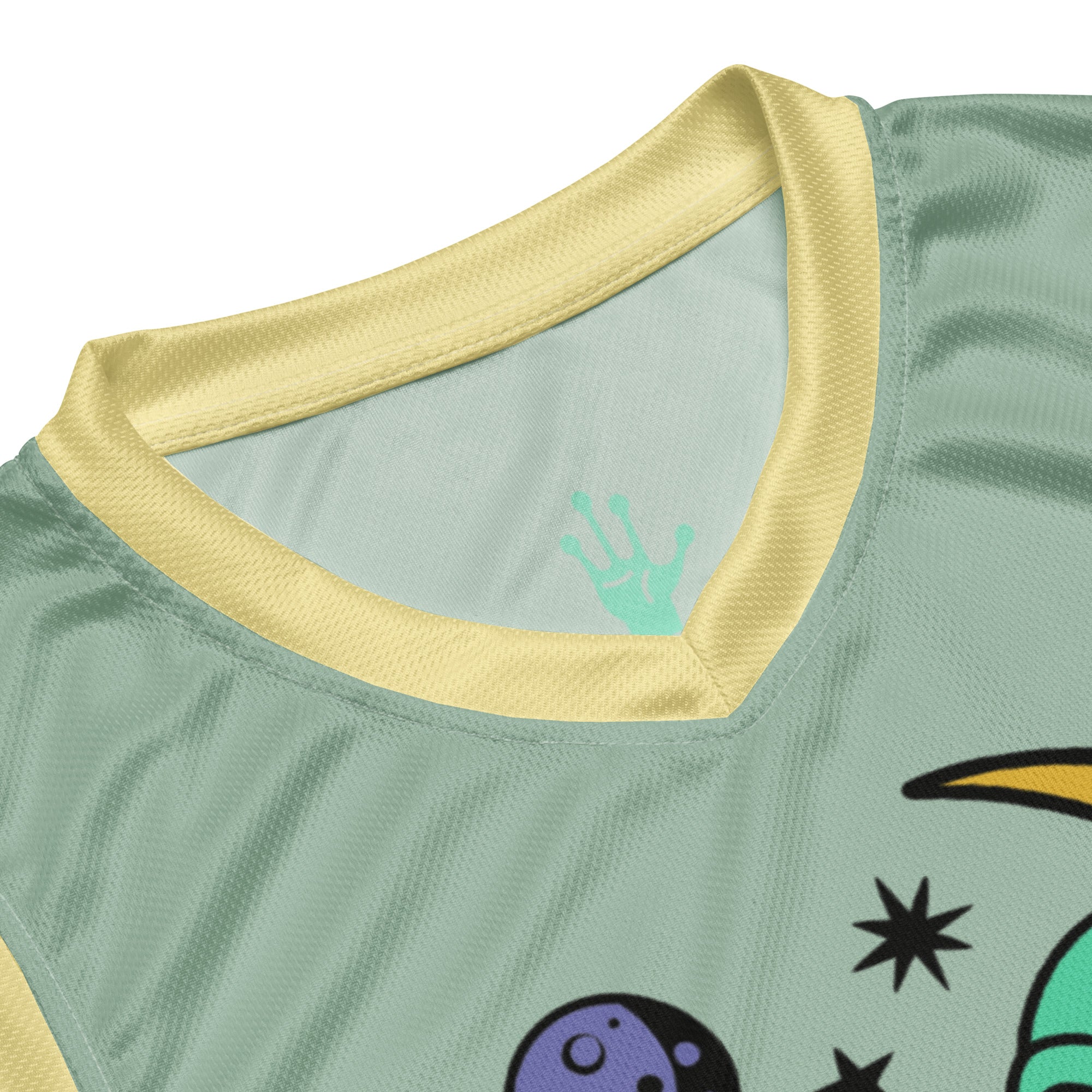 Ein lebhaftes, salbei grünes Basketballtrikot, akzentuiert durch frische, sonnengelbe Streifen an den Seiten und am Kragen. Das Herzstück des Trikots ist eine skurrile Grafik: Ein grünes Alien, entspannt auf einer leuchtenden, gelben Mondsichel, mit einer Zigarette im Mundwinkel. Um den Mond herum tanzen stilisierte Sterne und Planeten, die dem Design eine kosmische Note verleihen.n.