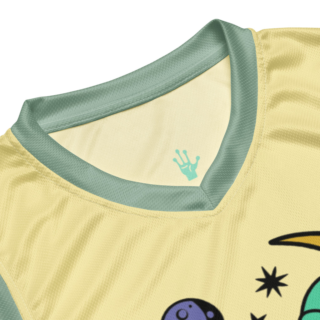 Ein lebhaftes, sonnengelbes Basketballtrikot, akzentuiert durch frische, mintgrüne Streifen an den Seiten und am Kragen. Das Herzstück des Trikots ist eine skurrile Grafik: Ein grünes Alien, entspannt auf einer leuchtenden, gelben Mondsichel, mit einer Zigarette im Mundwinkel. Um den Mond herum tanzen stilisierte Sterne und Planeten, die dem Design eine kosmische Note verleihen.