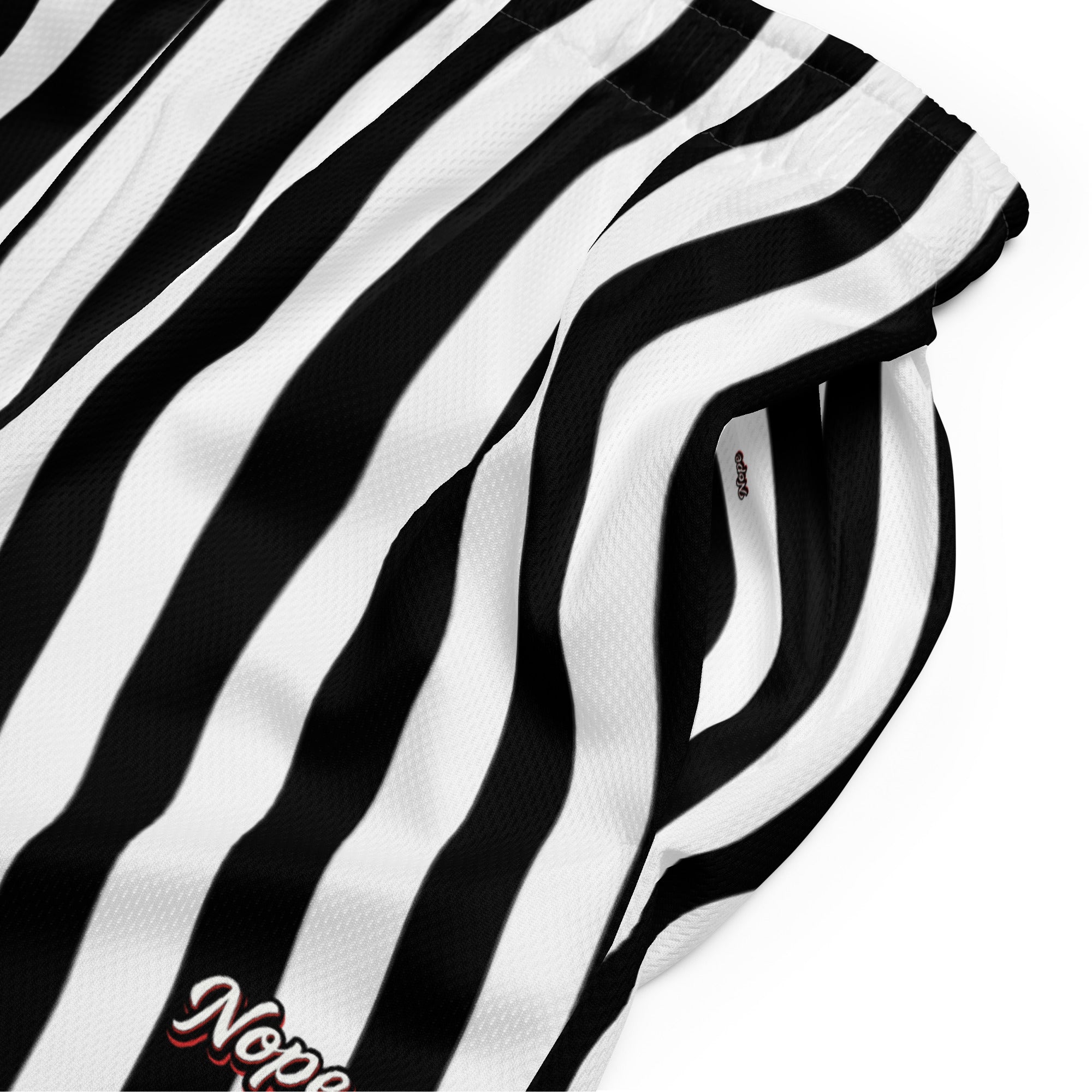Schwarz-weiß gestreifte Mesh-Sportshorts mit elastischem Bund. Am unteren rechten Bein steht in weißer Schrift mit rotem Schatten und schwarzem Rand das Wort "Nope".