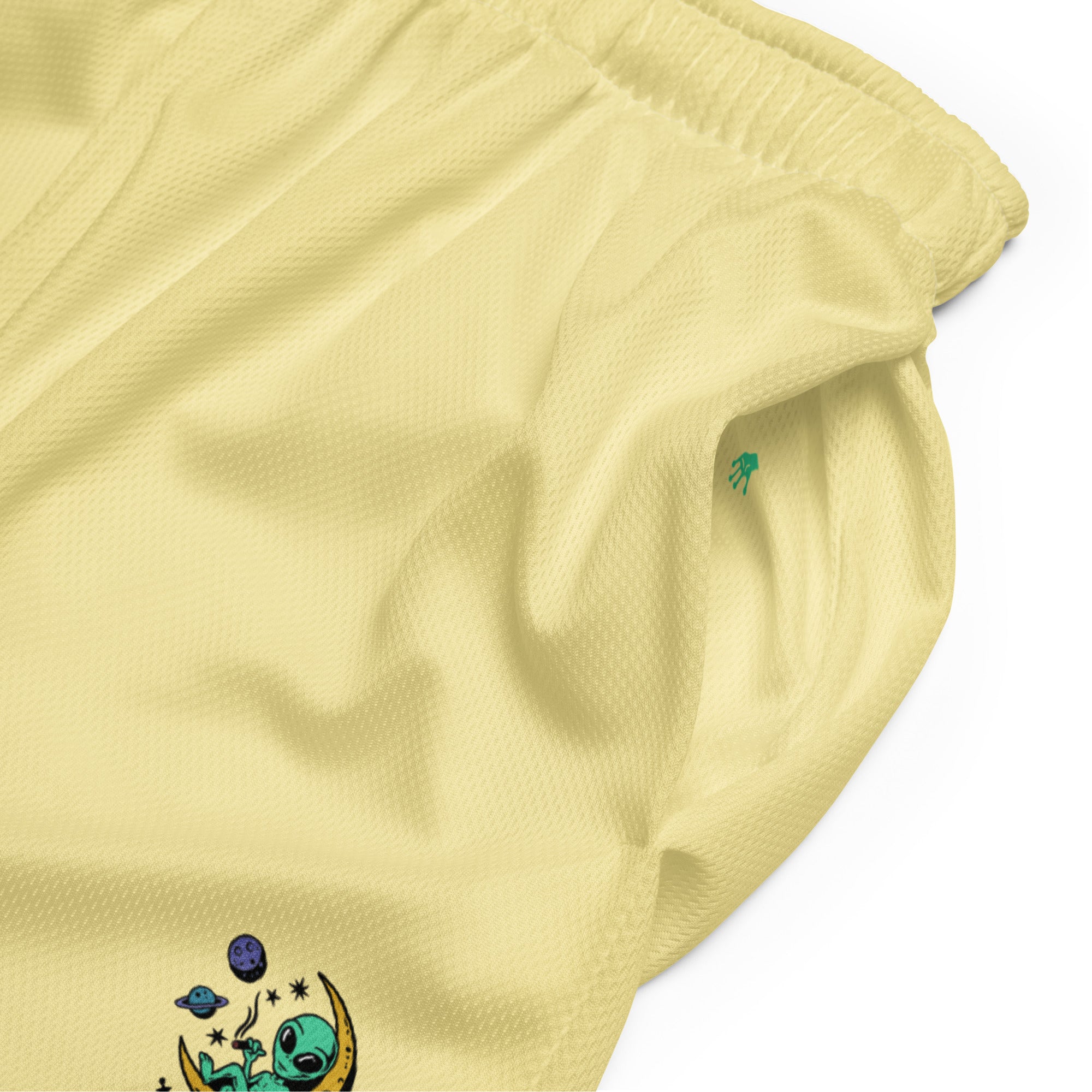 leuchtend sonnengelbe Basketballshorts, die auf dem linken Hosenbein das farbenfrohe "Chilling Vibes"-Logo mit einem grünen Alien auf einem gelben Halbmond zeigen, umgeben von Sternen und Planeten. Die Shorts bestehen aus glattem Sportmaterial.
