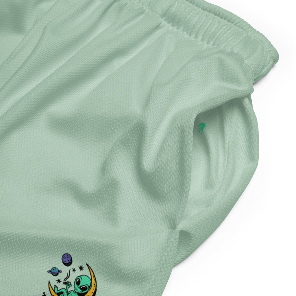 Ein Paar mintgrüne Basketballshorts, die auf dem linken Hosenbein das farbenfrohe "Chilling Vibes"-Logo mit einem grünen Alien auf einem gelben Halbmond zeigen, umgeben von Sternen und Planeten. Die Shorts bestehen aus glattem Sportmaterial.