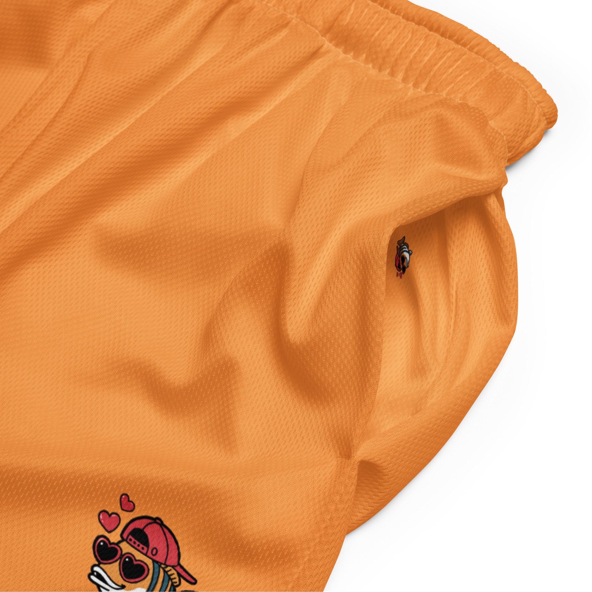 Orange farbene Basketballshorts aus glattem Sportgewebe. Auf dem linken Oberschenkel ist eine kleinere, detaillierte Version des "Loving Fishy" Cartoon-Fisches mit Cap und Herz-Sonnenbrille abgebildet.
