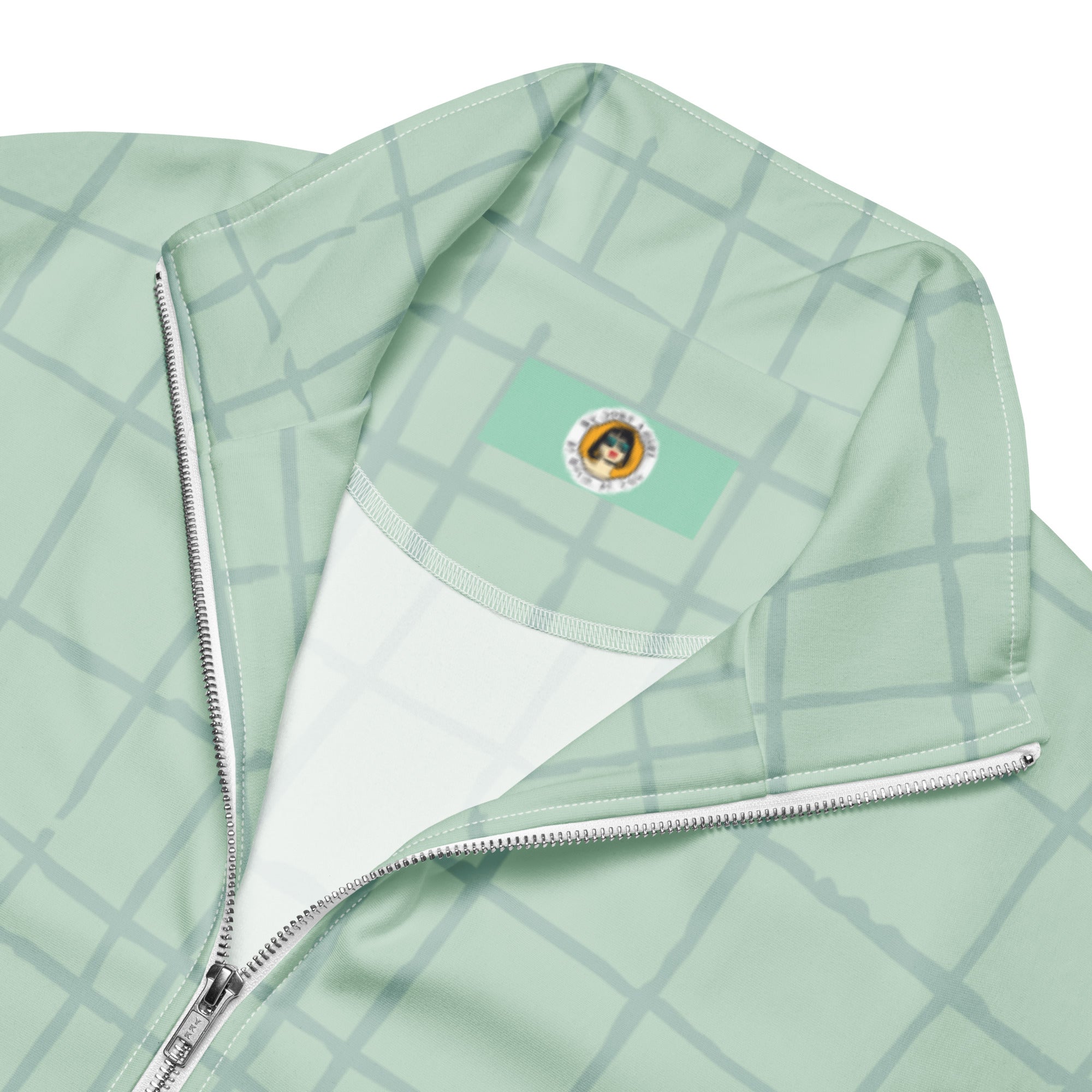 Trainingsjacke in hellem Mintgrün mit einem dezenten, hellgrauen Gittermuster. Die Jacke hat einen Stehkragen und einen durchgehenden Reißverschluss.