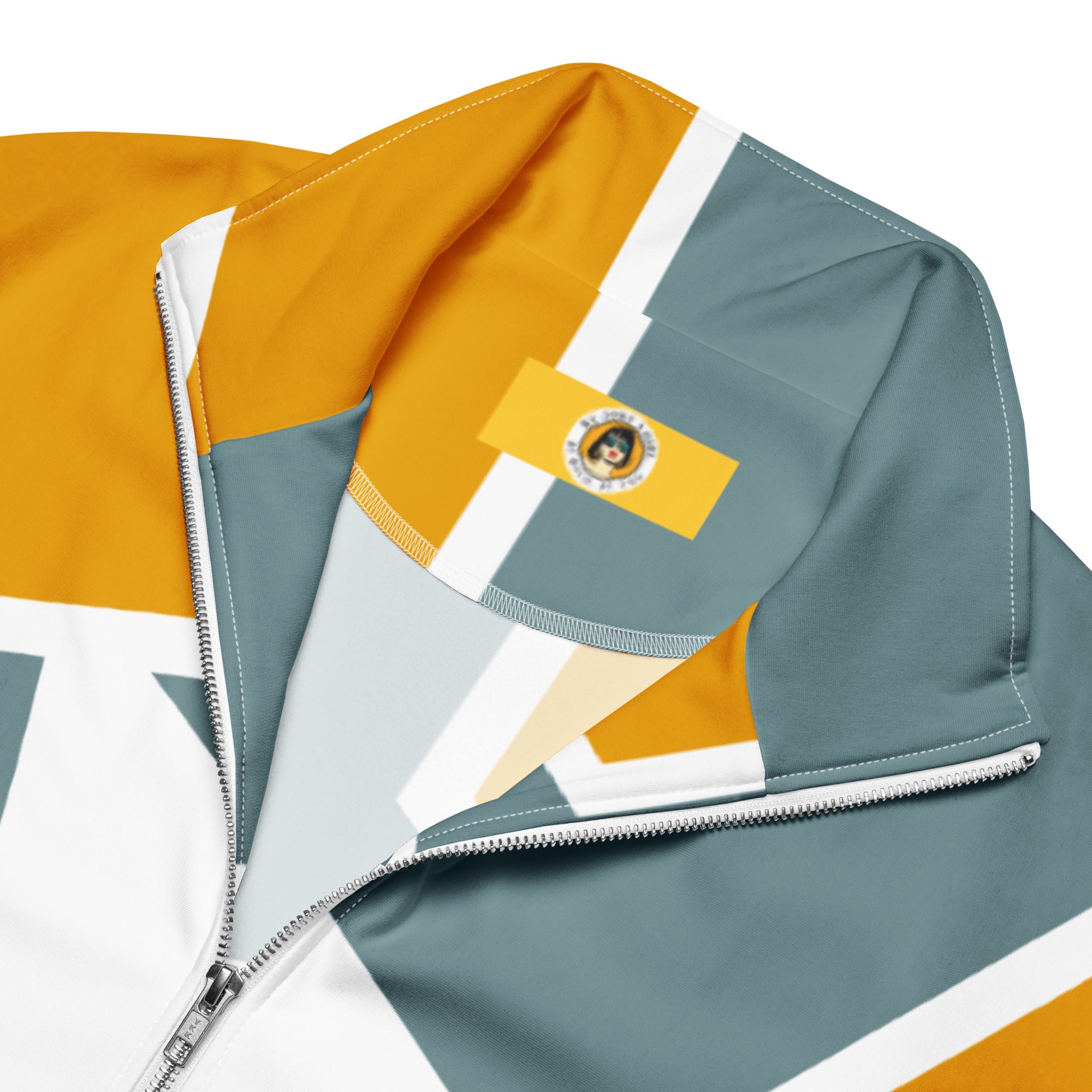 Trainingsjacke mit einem abstrakten, geometrischen Muster in den Farben Gelb, Grau und Weiß. Die Jacke hat einen Stehkragen und einen durchgehenden Reißverschluss.