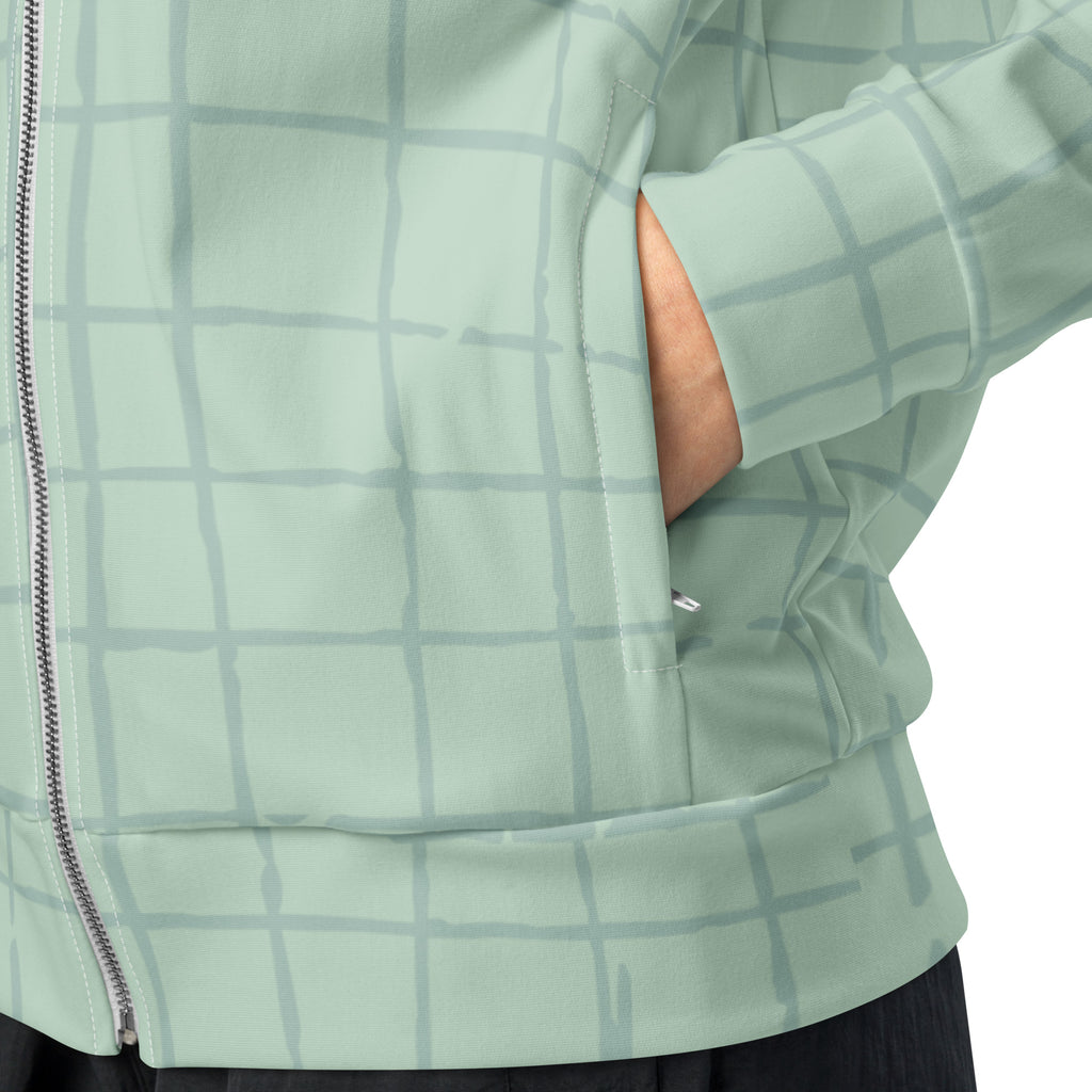 Trainingsjacke in hellem Mintgrün mit einem dezenten, hellgrauen Gittermuster. Die Jacke hat einen Stehkragen und einen durchgehenden Reißverschluss.