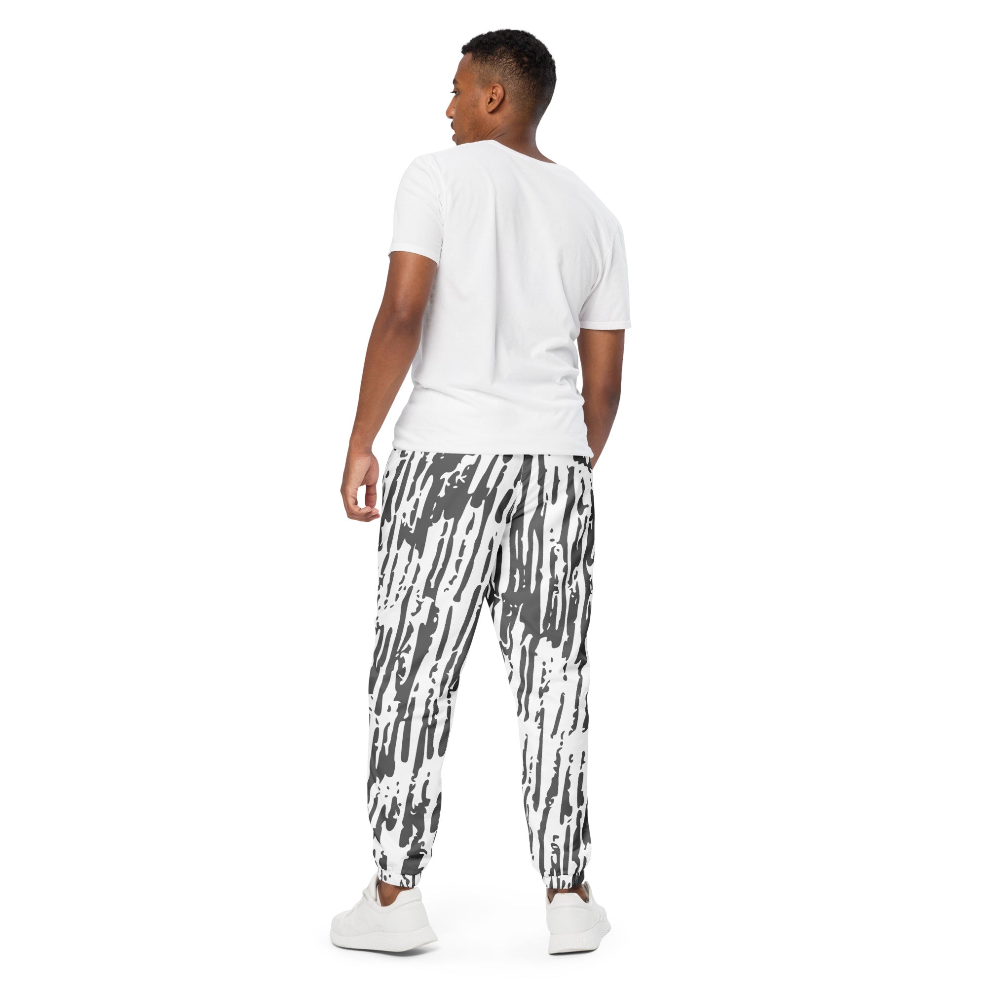 Schwarz-weiße Trainingshose mit einem abstrakten, vertikalen Strichmuster. Die Hose hat einen elastischen Bund und Bündchen an den Beinabschlüssen.