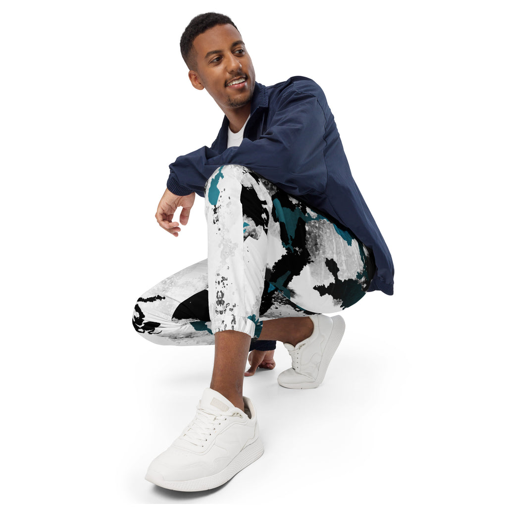 Herren-Trainingshose mit einem Inkstorm Muster in Schwarz, Grau, Türkis und Weiß. Die Hose hat einen elastischen Bund und Bündchen an den Beinabschlüssen.