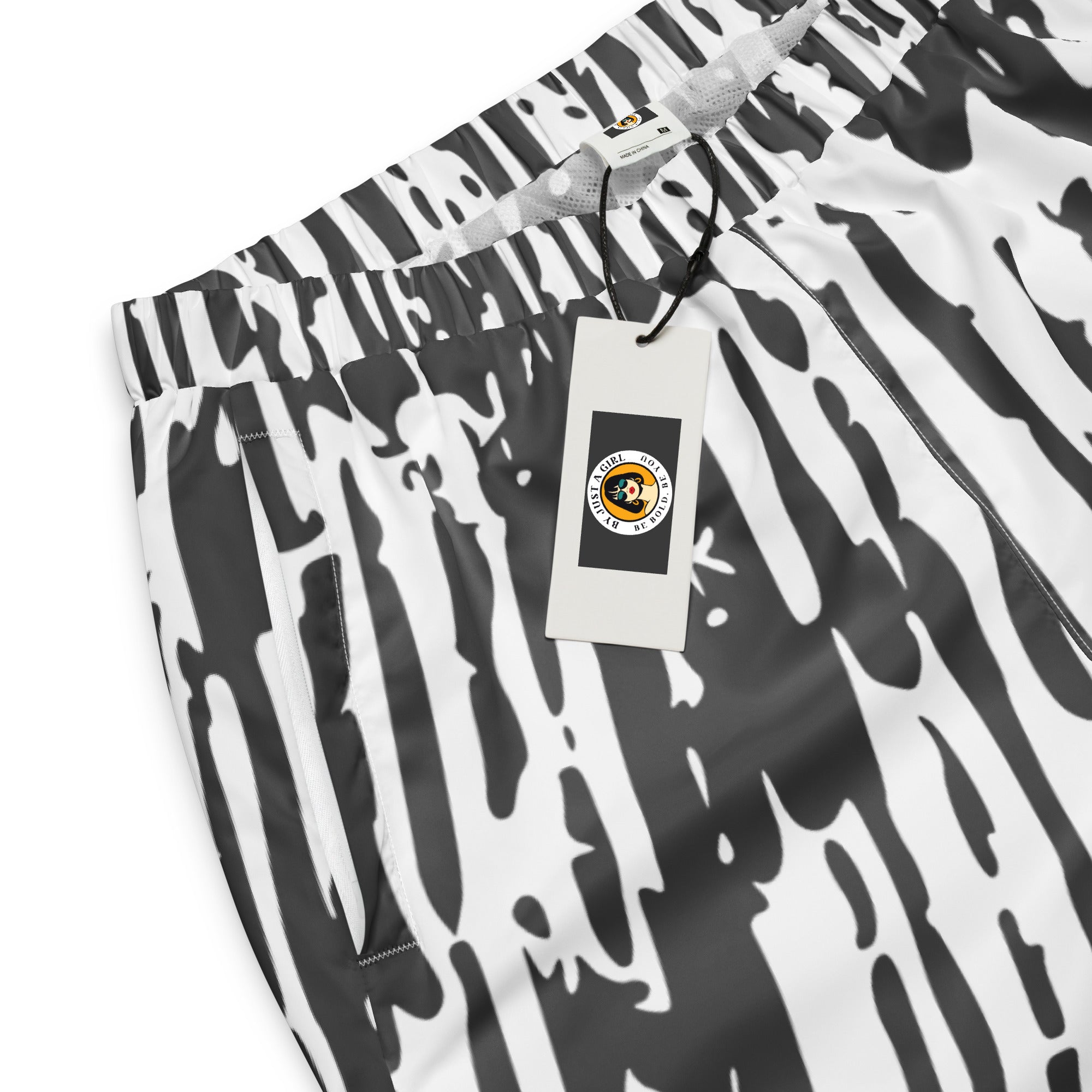 Schwarz-weiße Trainingshose mit einem abstrakten, vertikalen Strichmuster. Die Hose hat einen elastischen Bund und Bündchen an den Beinabschlüssen.