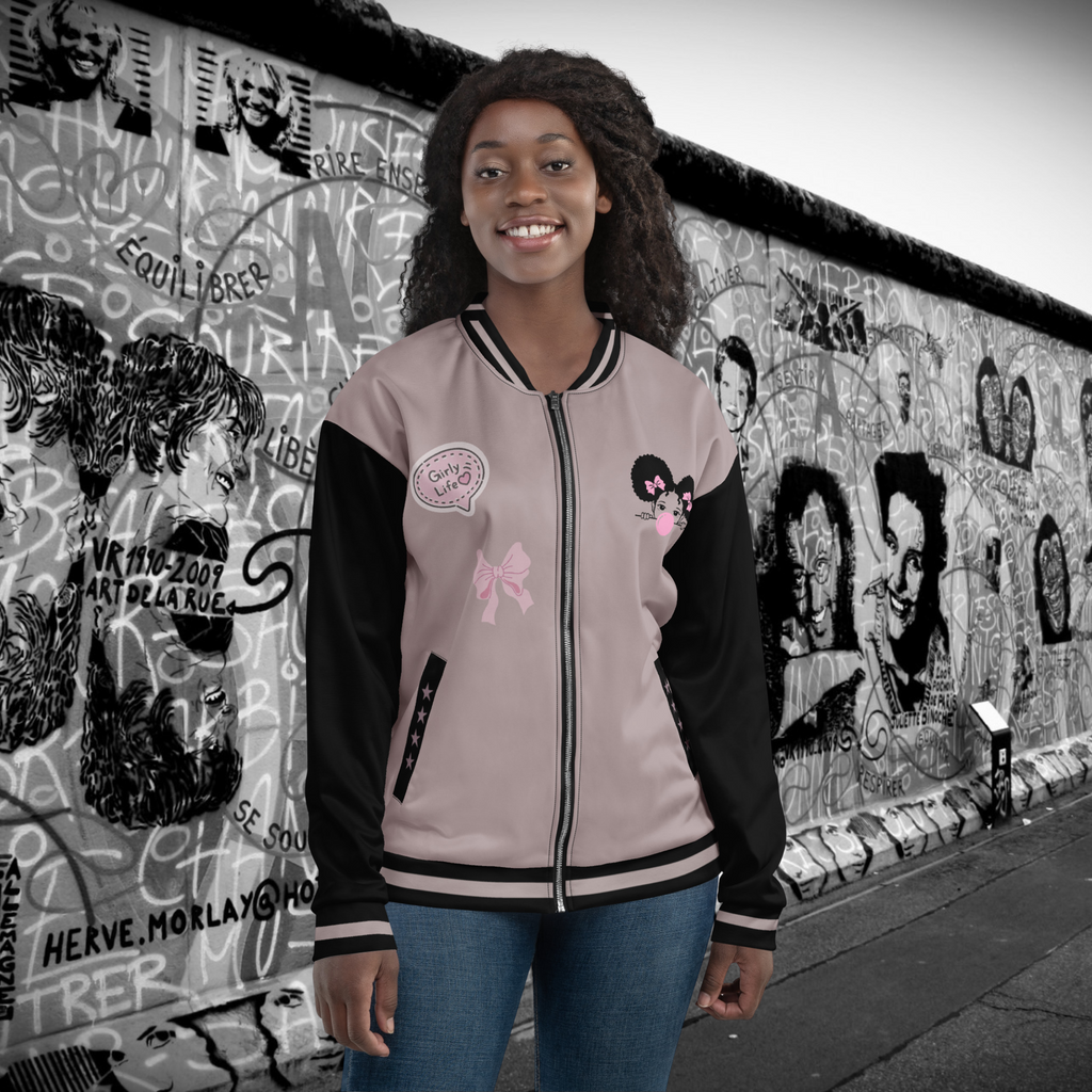 Die "Bubble Girl" Jacke im College Style gezeigt von einem weiblichen Model in der Vorderansicht. Auf der linken Brust ist ein kleines Afro Mädchen mit MM Haaren und rosa Schleifchen im Haar. Es schaut entspannt und macht eine riesen Kaugummiblase in Pink. Auf der rechten Seite sind 2 Elemente einemal eine Schleife im dezenten Style sowie ein Batch aufnäher gedruckt im Girlie Life Stil. Auf den Taschenbündchen sind jeweils dezent passende 4 Sterne zu sehen. By Just a Gril.