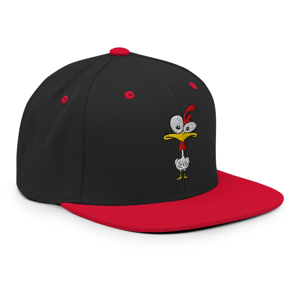 Eine klassische, zweifarbige Snapback-Cap mit flachem Schirm. Auf der Vorderseite ist ein gesticktes Cartoon-Motiv eines Huhns zu sehen, das einen hellen Kopf, große Augen, einen farbigen Kamm und einen Schnabel sowie eine kleine stilisierte Geste am Hals hat. Der obere Teil der Kappe ist dunkel, während der Schirm und der obere Knopf eine leuchtende Kontrastfarbe aufweisen.