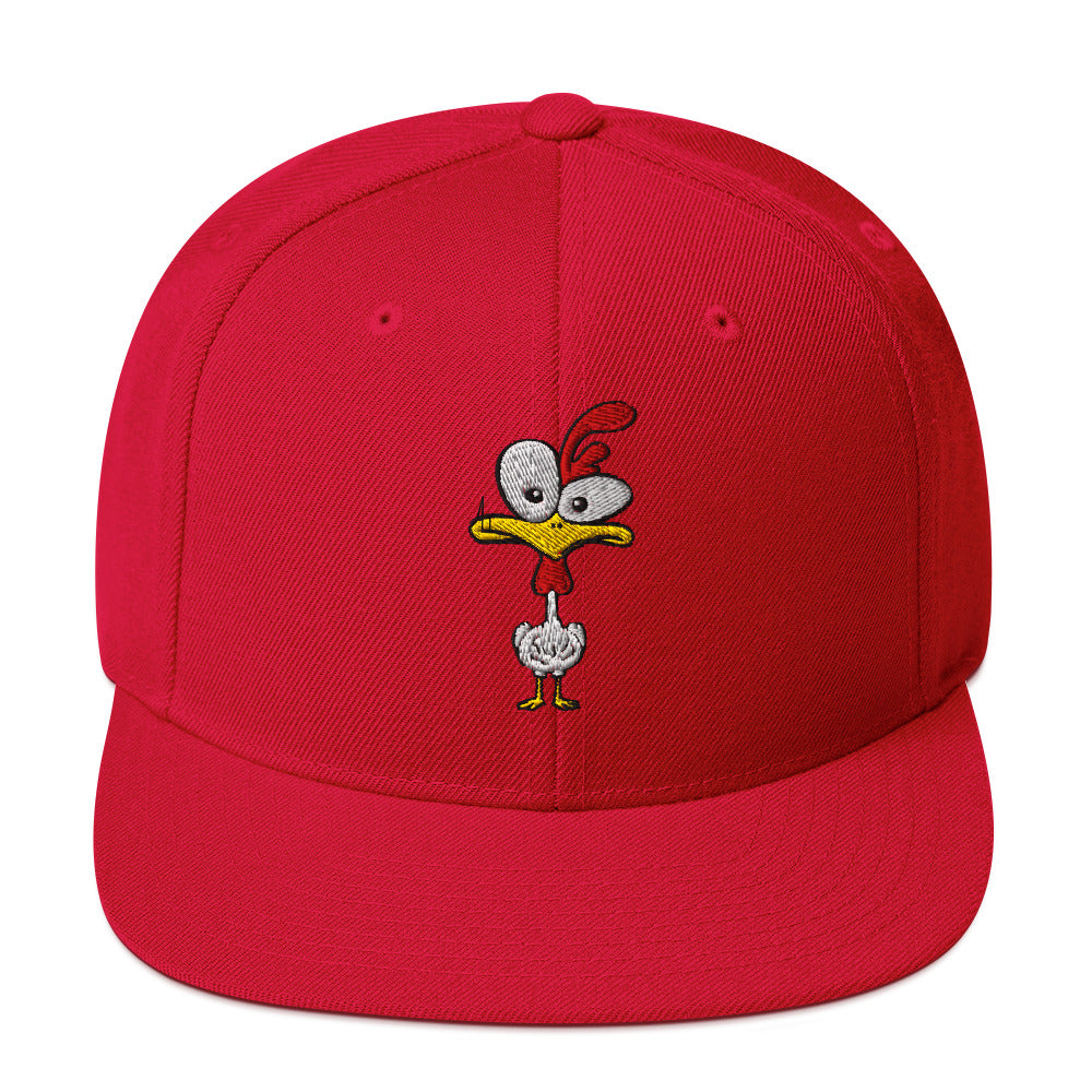 Eine klassische, farbige Snapback-Cap mit flachem Schirm. Auf der Vorderseite ist ein gesticktes Cartoon-Motiv eines Huhns zu sehen, das einen hellen Kopf, große Augen, einen farbigen Kamm und einen Schnabel sowie eine kleine stilisierte Geste am Hals hat. Der obere Teil der Kappe ist dunkel, während der Schirm und der obere Knopf eine leuchtende Kontrastfarbe aufweisen.