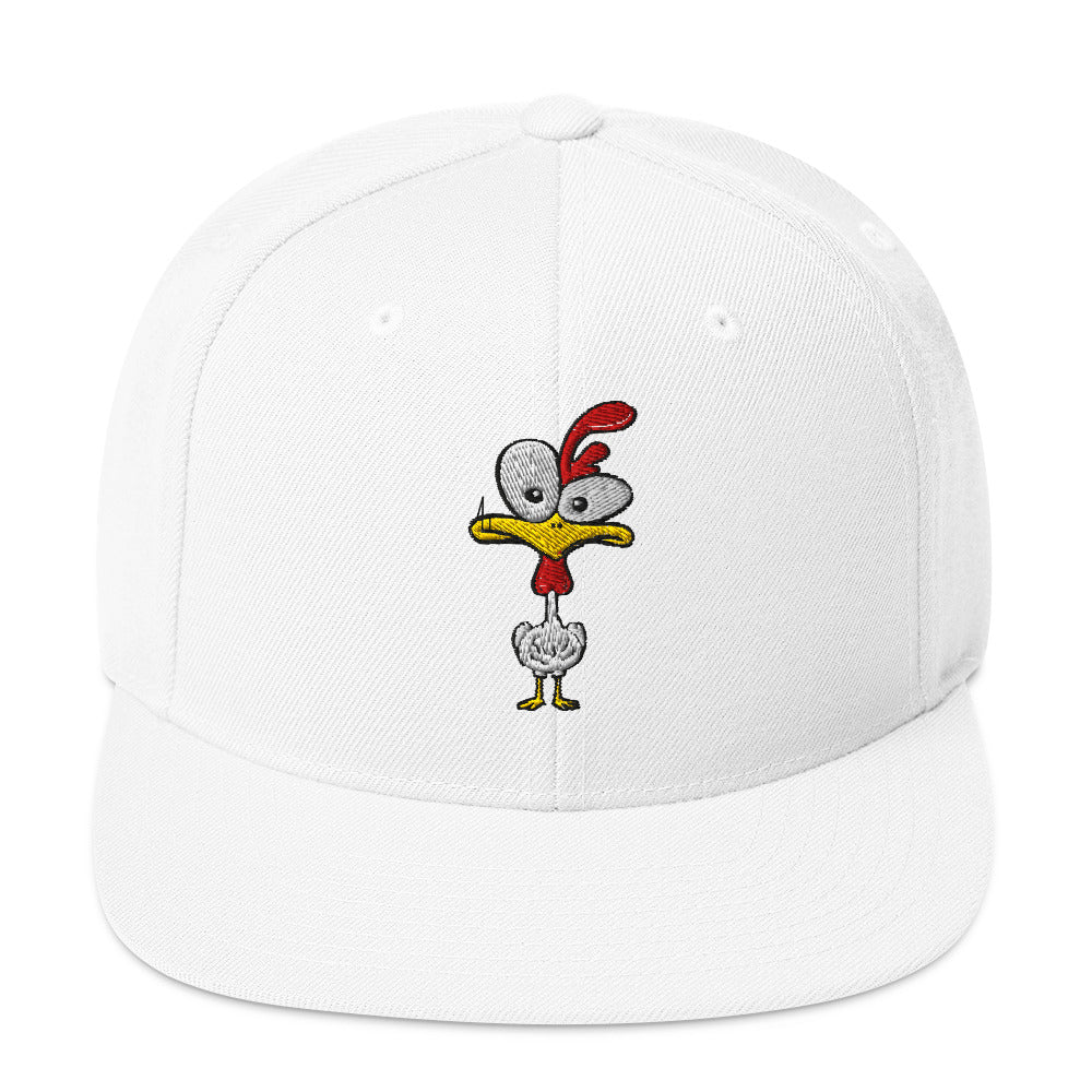 Eine klassische, zweifarbige Snapback-Cap mit flachem Schirm. Auf der Vorderseite ist ein gesticktes Cartoon-Motiv eines Huhns zu sehen, das einen hellen Kopf, große Augen, einen farbigen Kamm und einen Schnabel sowie eine kleine stilisierte Geste am Hals hat. Der obere Teil der Kappe ist dunkel, während der Schirm und der obere Knopf eine leuchtende Kontrastfarbe aufweisen.