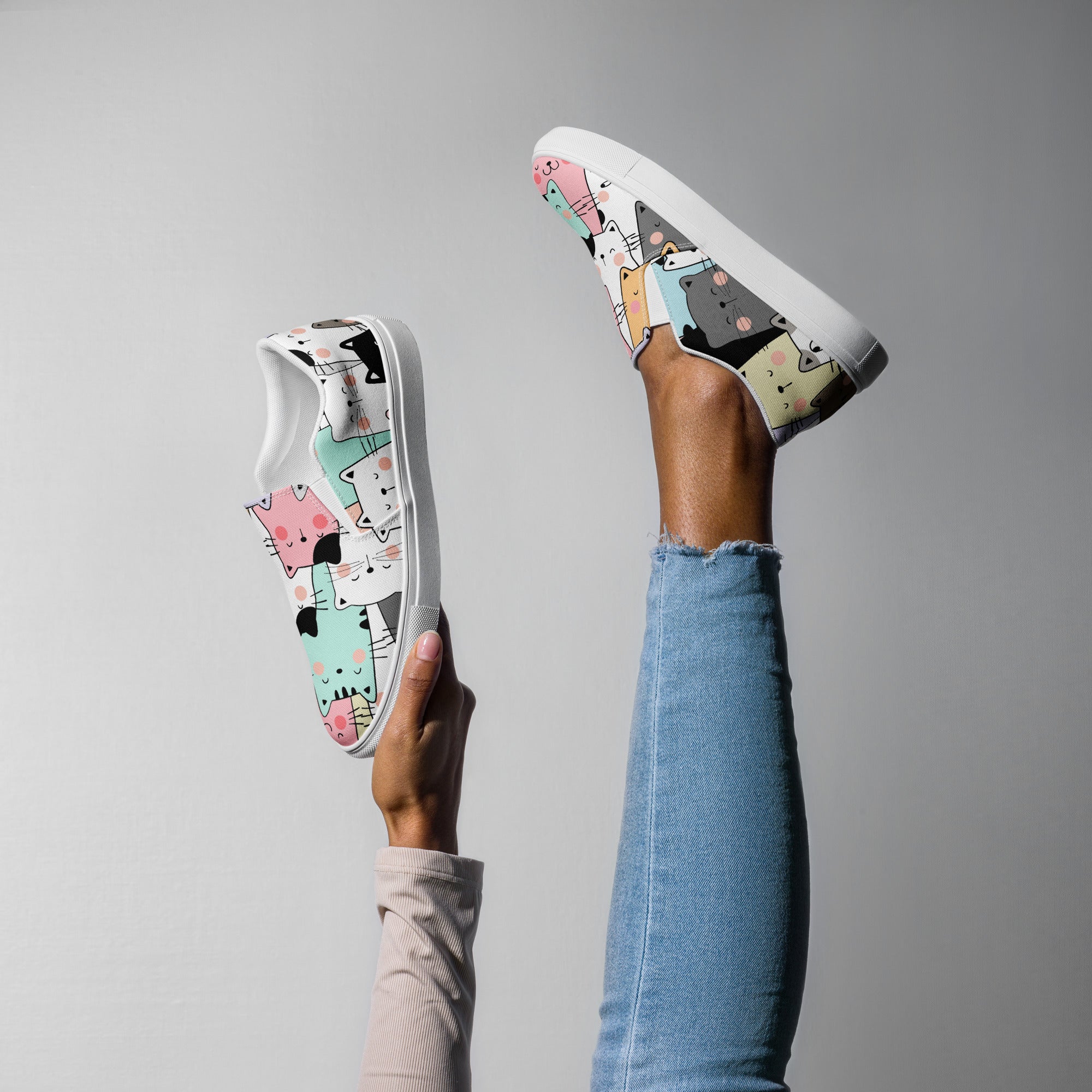 Ein weibliches Model zeigt tragend ein Bein in die Luft gestreckt und mit der anderen Hand den 2. Schuh zeigend mit einem Muster aus stilisierten, farbigen Katzen in Grau, Rosa, Orange, Mintgrün und Weiß. Designed, by Just a Girl.