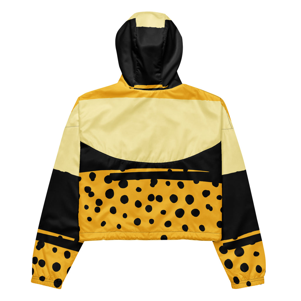 Ein Damen Cropped Windbreaker in Gelb, Schwarz und einem pastell gelb, mit einem auffälligen schwarzen Punktemuster auf der unteren gelben Hälfte. Die Jacke hat eine Kapuze, einen halben Reißverschluss, schwarze Kordeln und einen verstellbaren Saum. By Just a Girl.