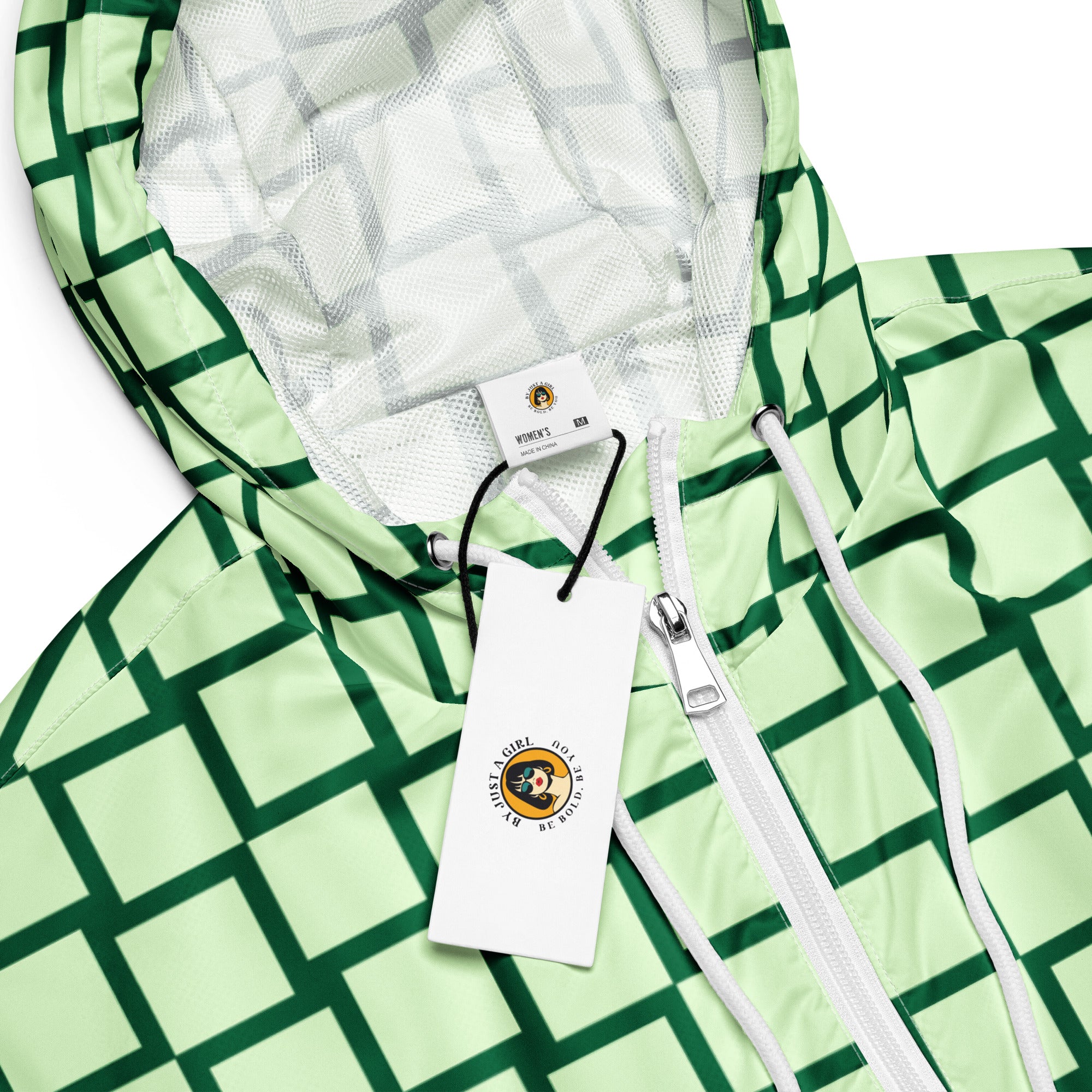 Ein Damen Cropped Windbreaker mit einem Schachbrettmuster in hellem Mintgrün und dunklem Grün. Die Jacke hat eine Kapuze, einen halben Reißverschluss mit weißen Kordeln und einen verstellbaren Saum. Mockup Kapuzen Ansicht mit Logo. By Just a Girl.