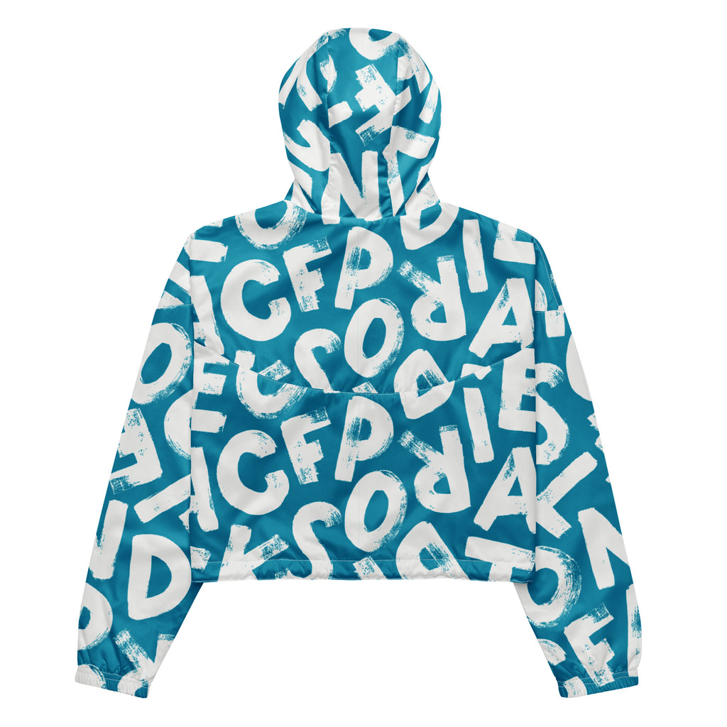 Ein Damen Cropped Windbreaker in Türkis mit einem Muster aus großen, weißen und unregelmäßig geformten Buchstaben. Die Jacke hat eine Kapuze, einen halben Reißverschluss, weiße Kordeln und einen verstellbaren Saum. Die Jacke ist flach ausgebreitet.
