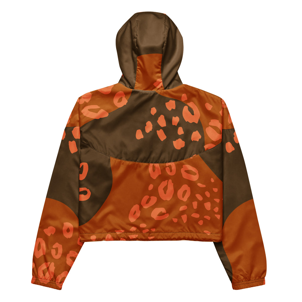 Ein Damen Cropped Windbreaker in Dunkelbraun und Orange mit einem abstrakten Muster aus unregelmäßigen Flecken und Formen, teilweise leopardenähnlich. Die Jacke hat eine Kapuze, einen halben Reißverschluss, schwarze Kordeln und einen verstellbaren Saum. Mockup Jacken Rückenansicht. By Just a Girl.