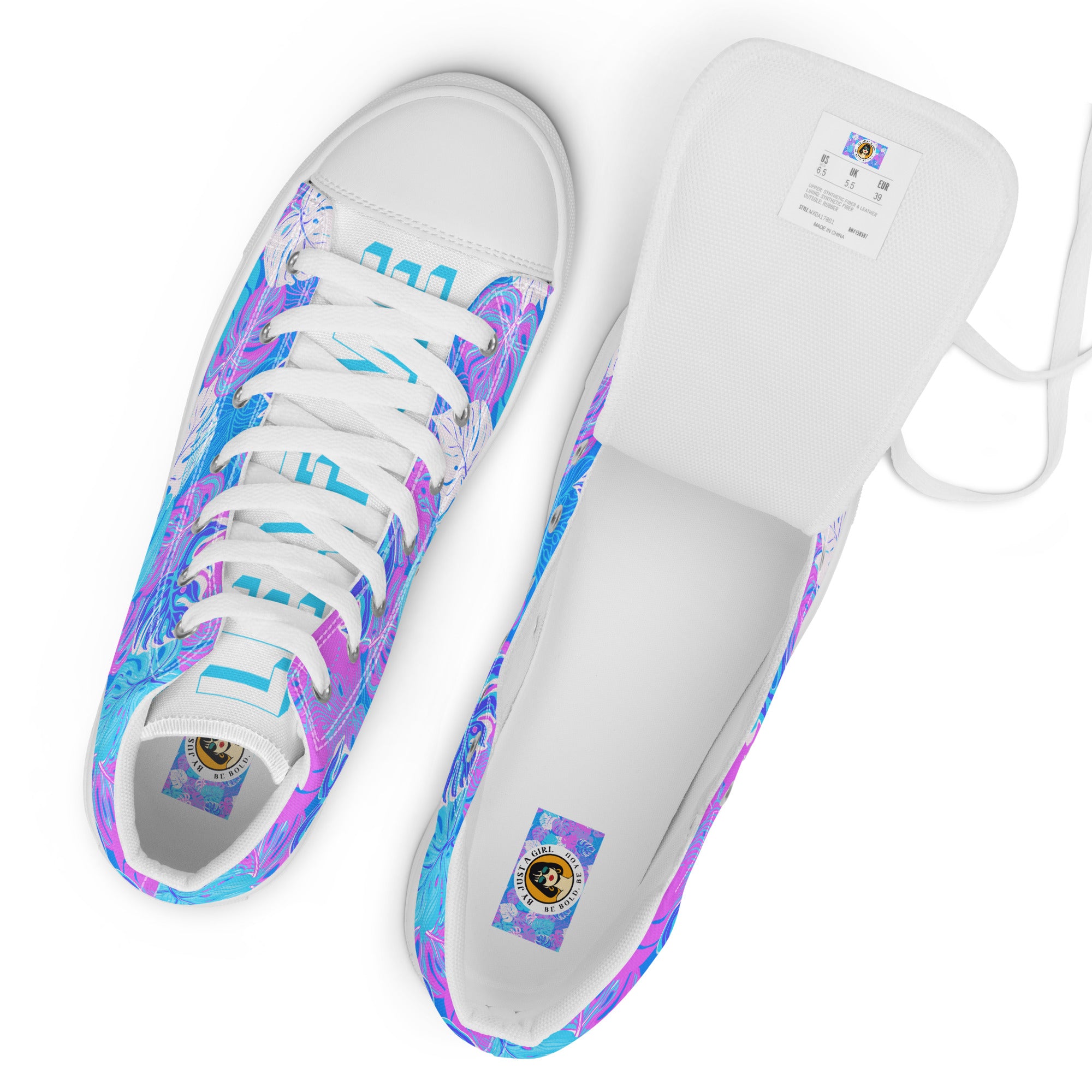 Ansicht von oben der High-Top-Canvas-Sneaker mit einem Muster aus tropischen Blättern in Blau, Lila und Pink. Die Sohlen, Zehenkappen und Schnürsenkel sind weiß. Die weißen Schuhzungen sind mit blauem Text "Leaf me" auf dem einen Schuh und "Wild" auf dem anderen beschriftet. Rechter Schuh ist offen und zeigt die Sicht auf das Fussbett mit Logo.  Designed, by Just a Girl.