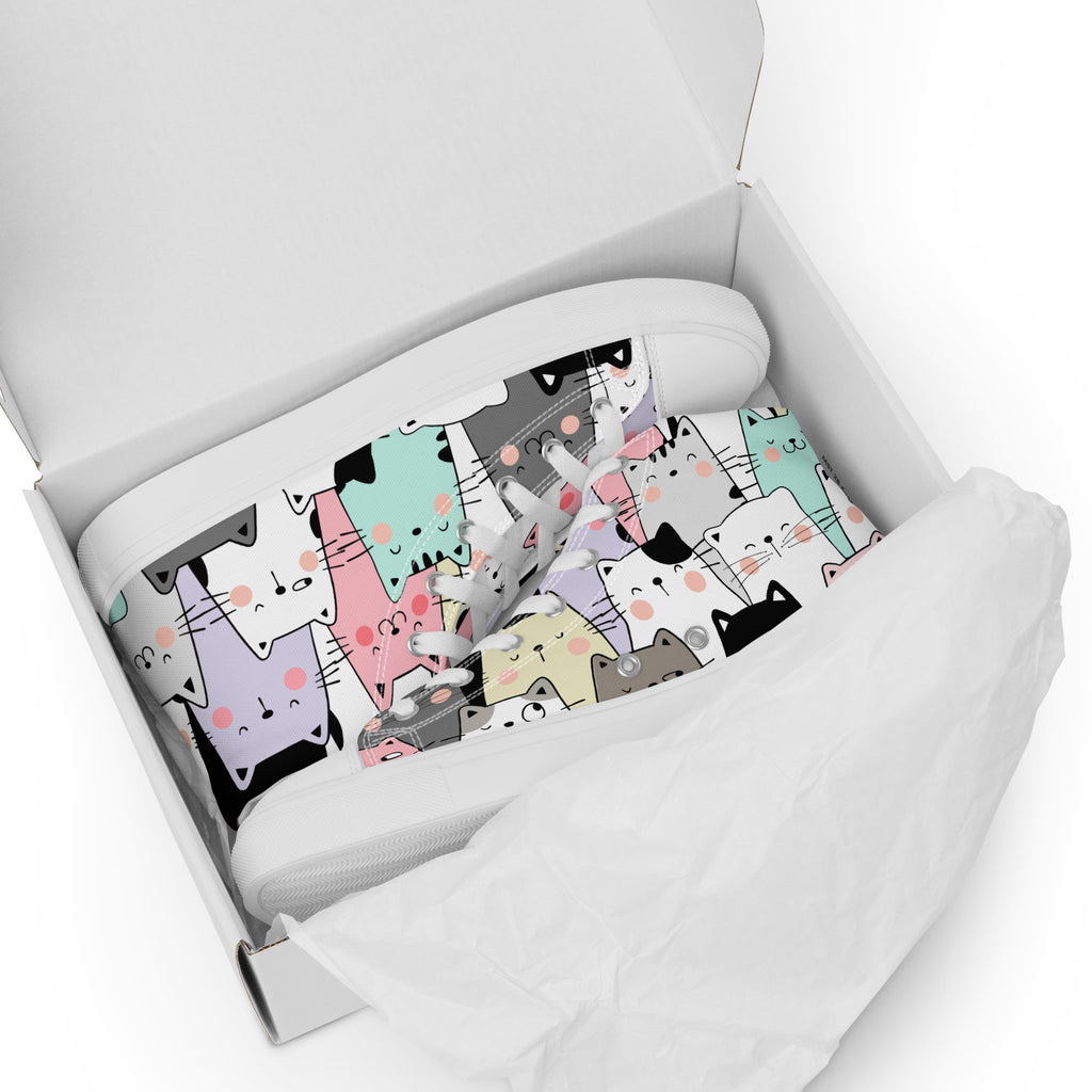 Ansicht liegend im Schuhkarton der weißen High-Top-Sneaker mit einem dichten Muster aus verschiedenfarbigen Cartoon-Katzenköpfen. Die Katzen sind in Pastelltönen wie Rosa, Hellblau, Grau und Violett gehalten. Die Schnürsenkel und Zehenkappen sind weiß. Designed, by Just a Girl.