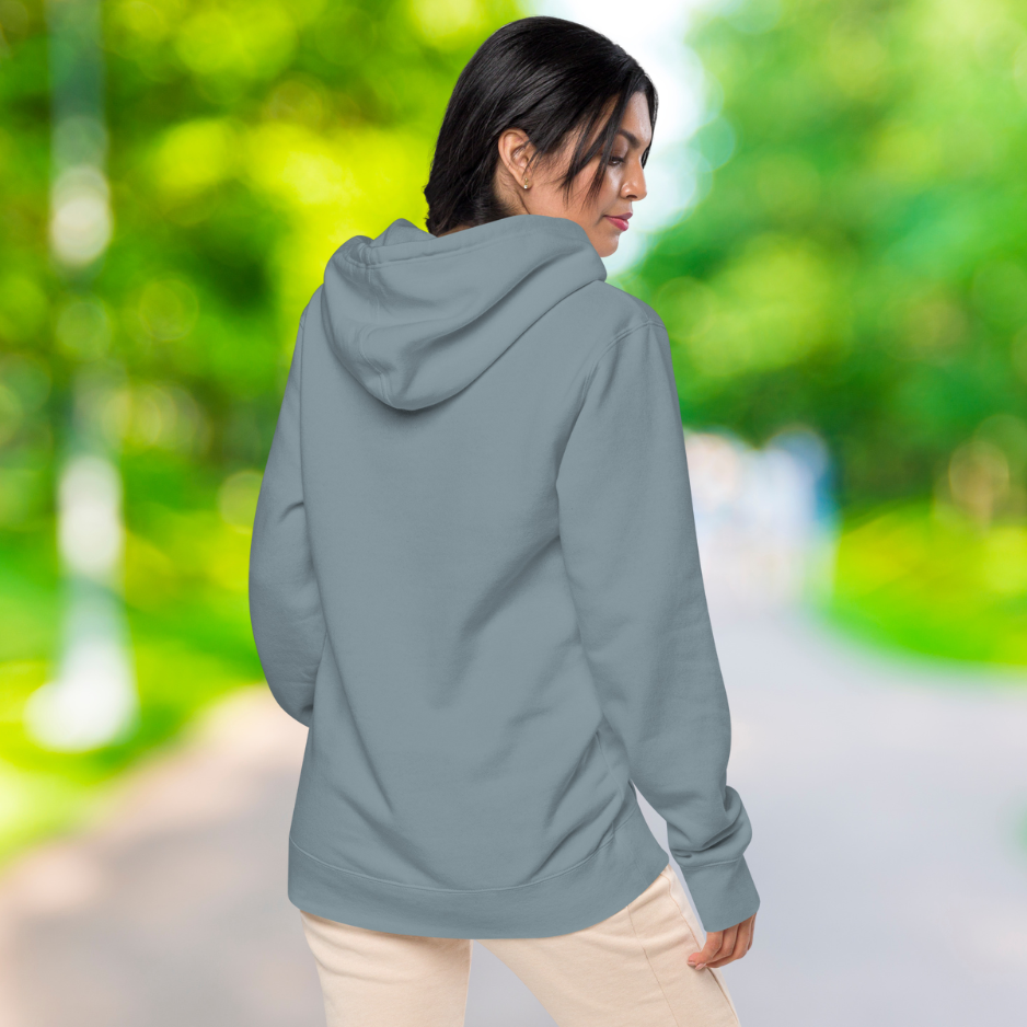 Ein weibliches Model zeigt sich draußen im freien mit den Schiefer blauen Kapuzenpullover von der Rückseite.