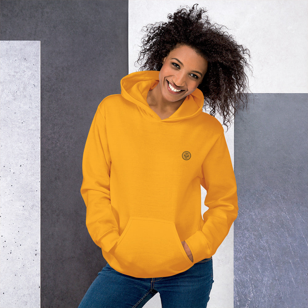 Ein weibliches Model zeigt sich mit dem Kapuzenpullover "The Golden One" Beide Hände lässig in der vorderen Beuteltasche. 
