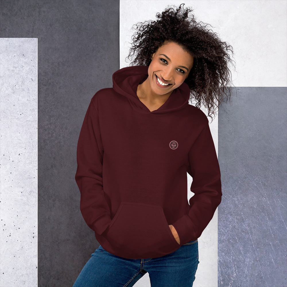 Ein weibliches Model zeigt sich mit dem Kapuzenpullover "The Maroon One" Beide Hände lässig in der vorderen Beuteltasche.