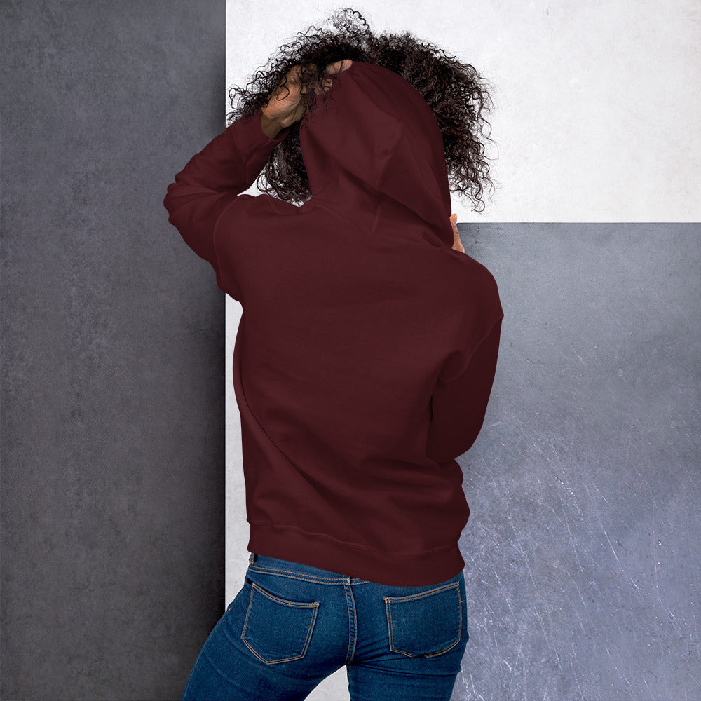 Ein weibliches Model zeigt sich von der Rückseite mit dem Kapuzenpullover "The Maroon One" und hält mit der linken Hand die Kapuze hoch.