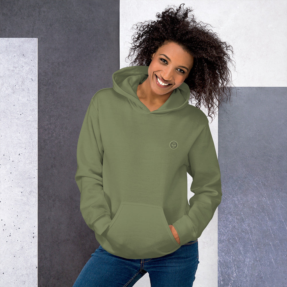 Ein weibliches Model zeigt sich mit dem Kapuzenpullover "The Olive One" Beide Hände lässig in der vorderen Beuteltasche.