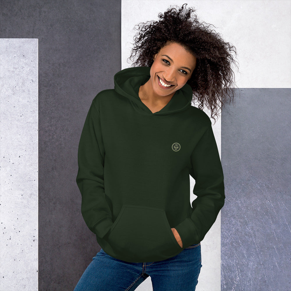 Ein weibliches Model zeigt sich mit dem Kapuzenpullover "The Pine One" Beide Hände lässig in der vorderen Beuteltasche.