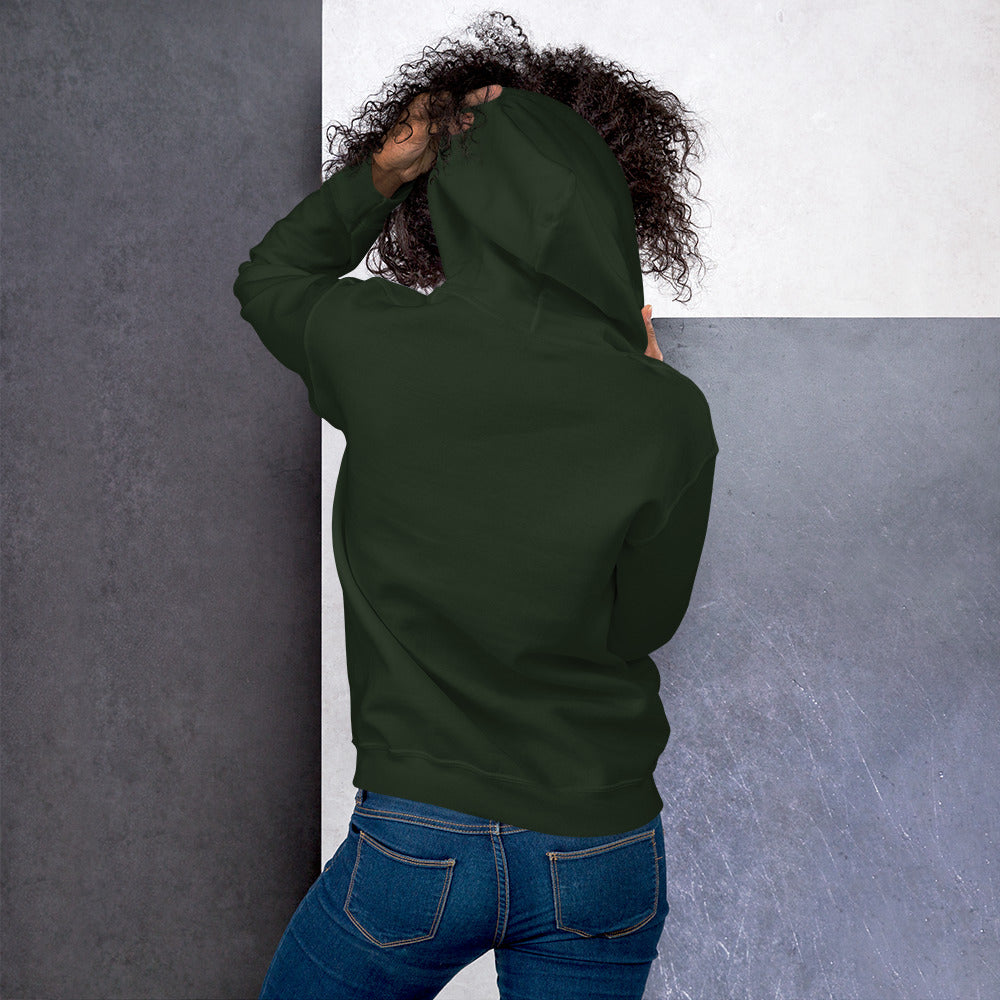 Ein weibliches Model zeigt sich von der Rückseite mit dem Kapuzenpullover "The Pine One" und hält mit der linken Hand die Kapuze hoch.