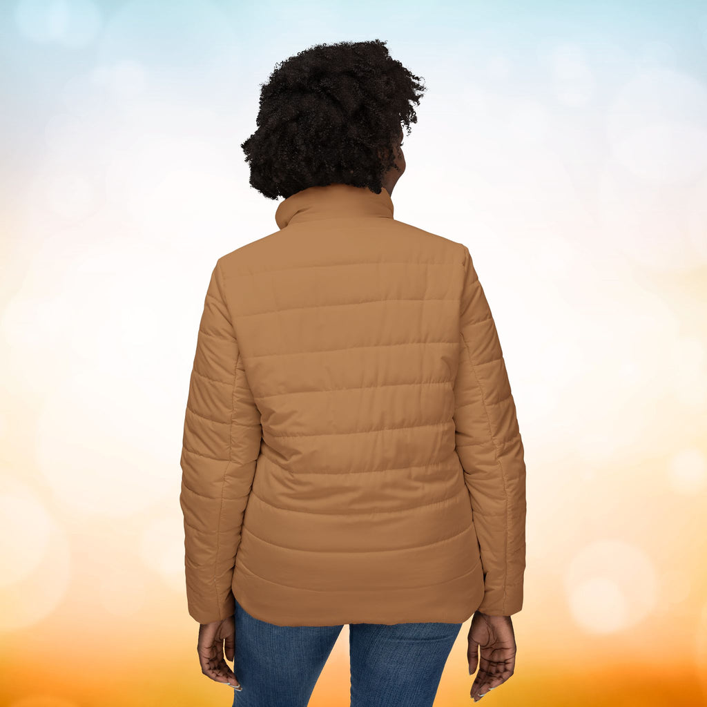 Ein weibliches Model zeigt die Damen-Pufferjacke mit der Rückenansicht in einem Persian-Orange farbton. Die Jacke ist horizontal gesteppt, hat eine glatte Oberfläche, einen hohen Stehkragen und einen durchgehenden Reißverschluss. Designed, by Just a Girl.

