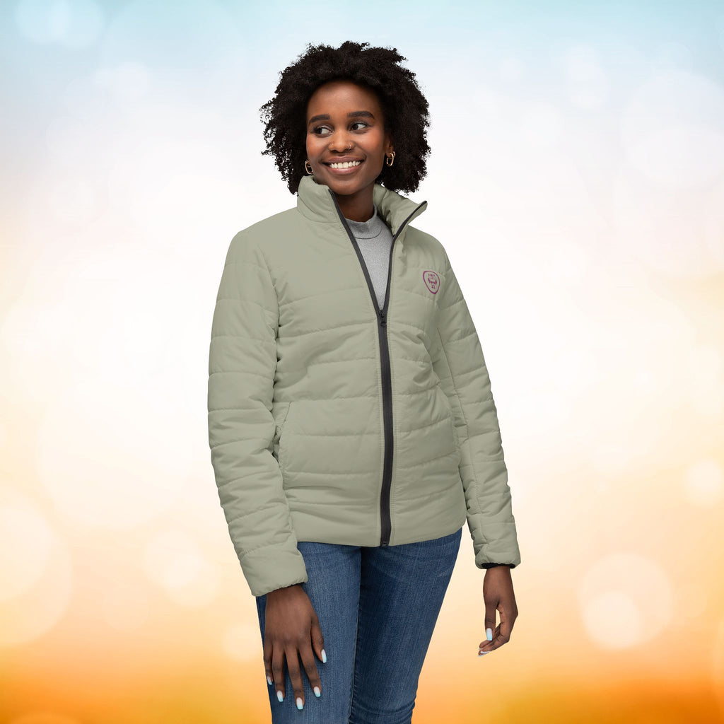  Ein weibliches Model trägt eine  Damen-Pufferjacke Ansicht von vorne in einem Ash Grey Farbton. Die Jacke ist horizontal gesteppt, hat eine glatte Oberfläche, einen hohen Stehkragen und einen durchgehenden Reißverschluss. Designed, by Just a Girl