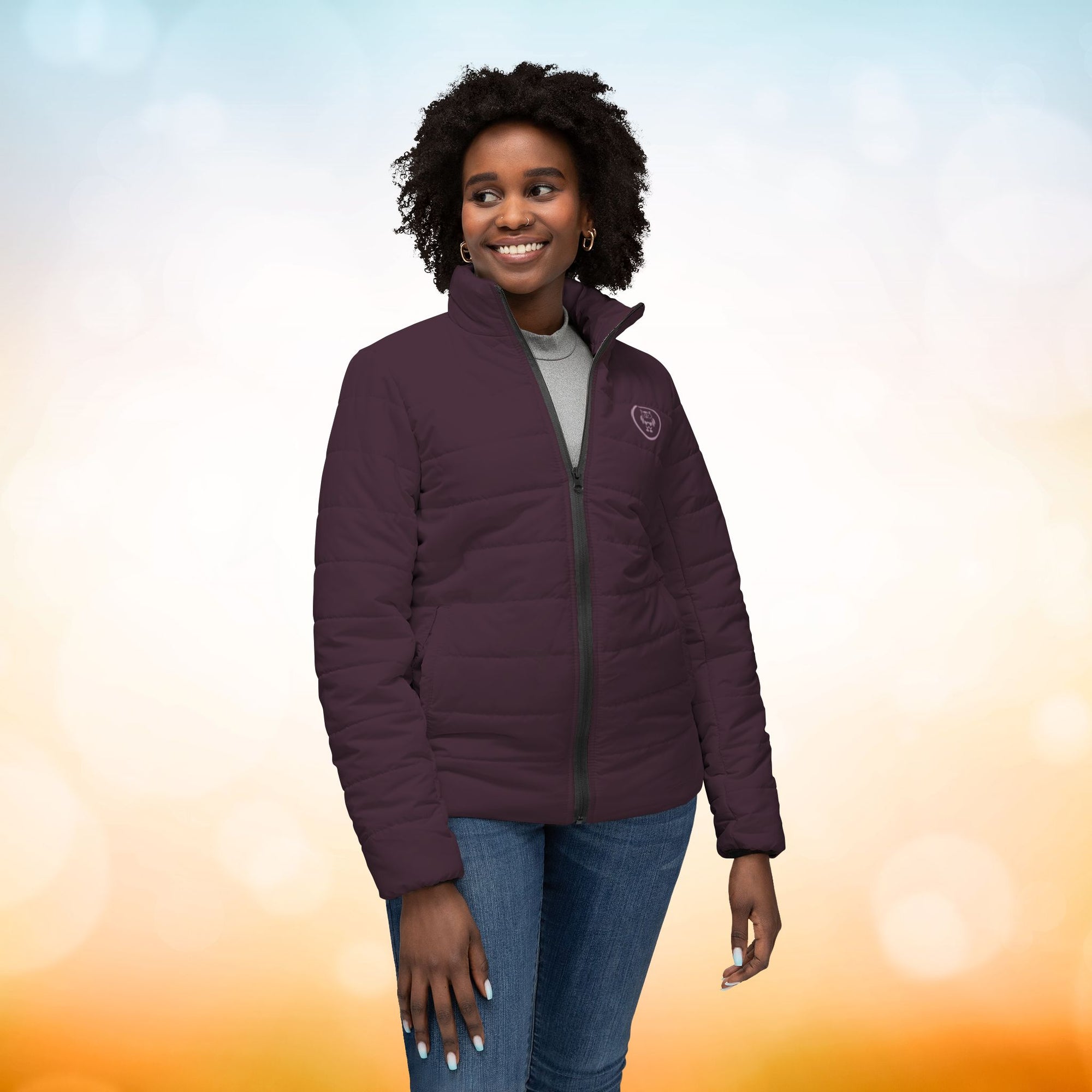 Ein weibliches Model zeigt von vorne eine Damen-Pufferjacke in einem Dark Plum Farbton. Die Jacke ist horizontal gesteppt, hat eine glatte Oberfläche, einen hohen Stehkragen und einen durchgehenden Reißverschluss. Designed, by Just a Girl

