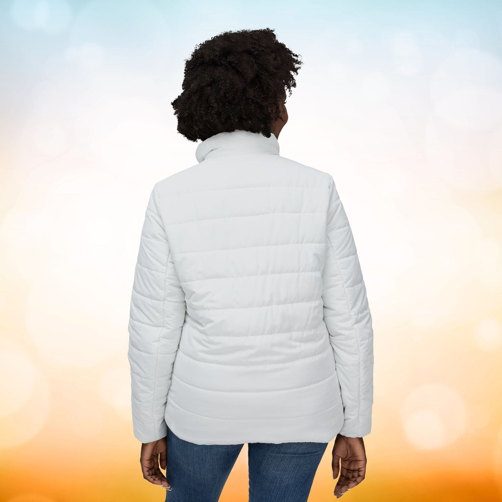 Ein weibliches Model zeigt sich von der Rückenansicht mit einer Damen-Pufferjacke  in einem Ivory Farbton. Die Jacke ist horizontal gesteppt, hat eine glatte Oberfläche, einen hohen Stehkragen und einen durchgehenden Reißverschluss. Designed, by Just a Girl

