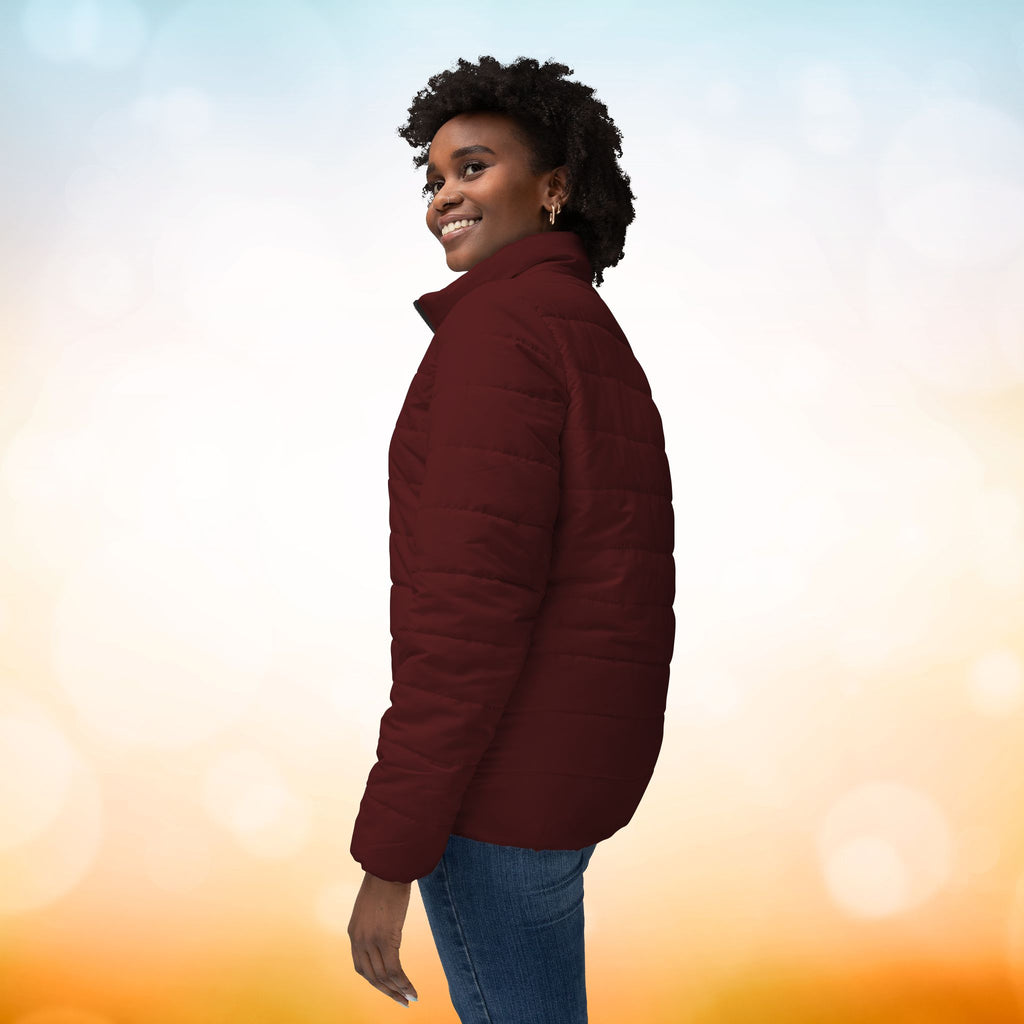 Ein weibliches Model trägt eine Damen-Pufferjacke in der Seitenansicht in einem Oxblood Farbton. Die Jacke ist horizontal gesteppt, hat eine glatte Oberfläche sowie einen hohen Stehkragen. Designed, by Just a Girl.

