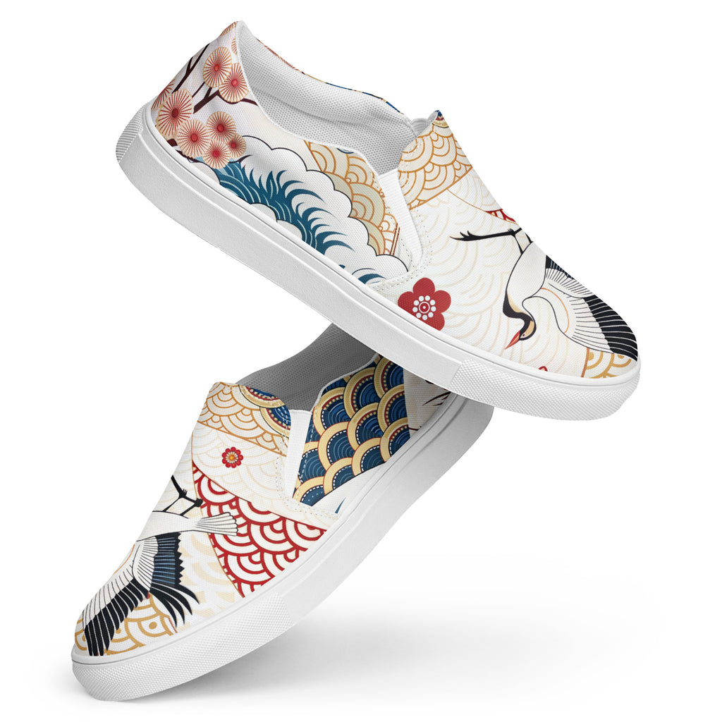 Ein Paar weiße Damen-Slip-on-Schuhe mit einem bunten Muster im japanischen Stil. Das Motiv zeigt Kraniche, Wellen, Kirschblüten und geometrische Muster. Die Schuhe schweben vor einem weißen Hintergrund. Designed, by Just a Girl