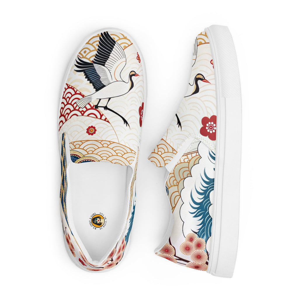 Ein Paar weiße Damen-Slip-on-Schuhe mit einem bunten Muster im japanischen Stil. Das Motiv zeigt Kraniche, Wellen, Kirschblüten und geometrische Muster. Die Schuhe werden angezeigt einer on oben und der andere liegt seitlich daneben vor einem weißen Hintergrund. Designed, by Just a Girl