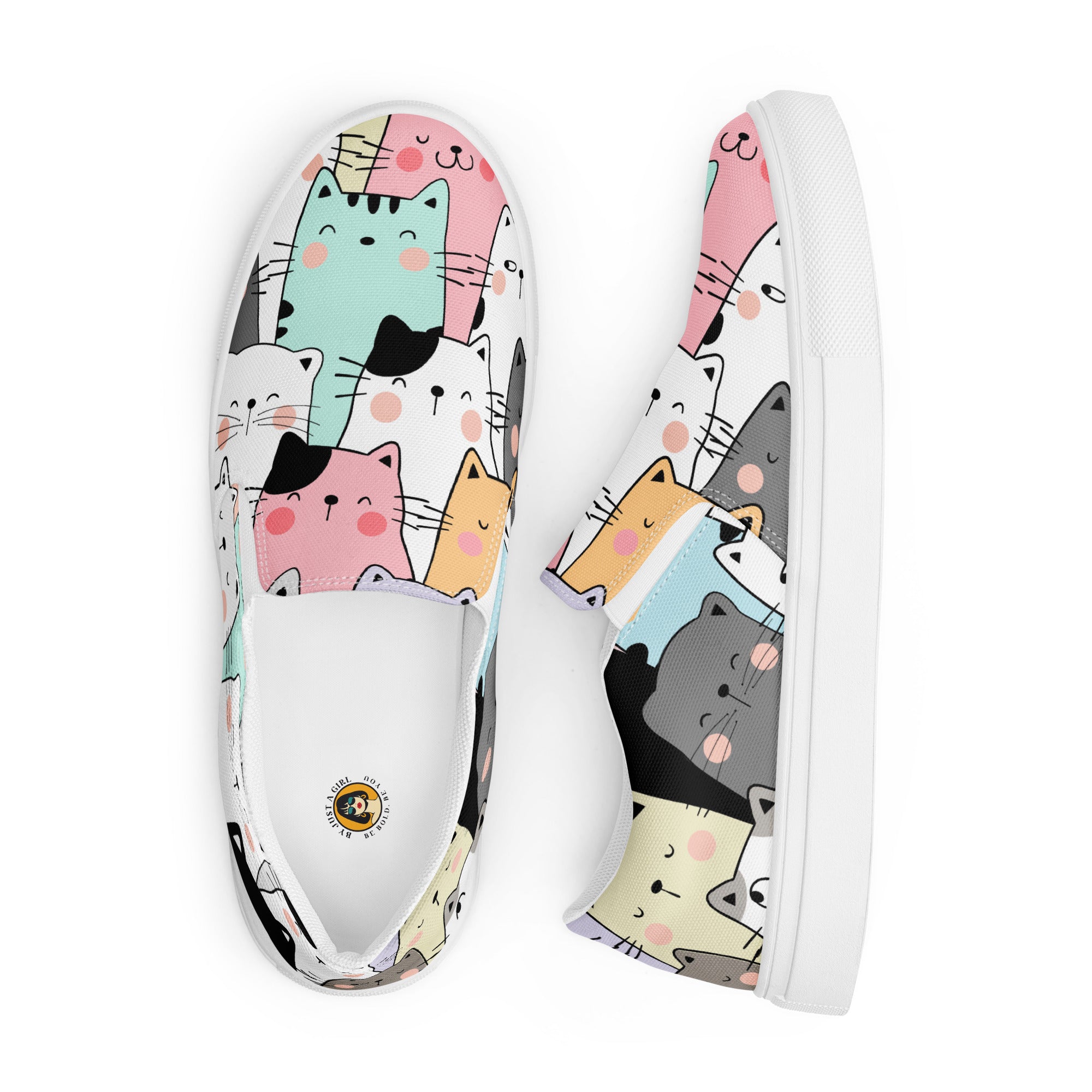 Ein Paar Damen Slip-on-Schuhe mit einem Muster aus stilisierten, farbigen Katzen in Grau, Rosa, Orange, Mintgrün und Weiß.  Die Schuhe werden angezeigt einer von oben und der andere liegt seitlich daneben vor einem weißen Hintergrund.. Designed, by Just a Girl.