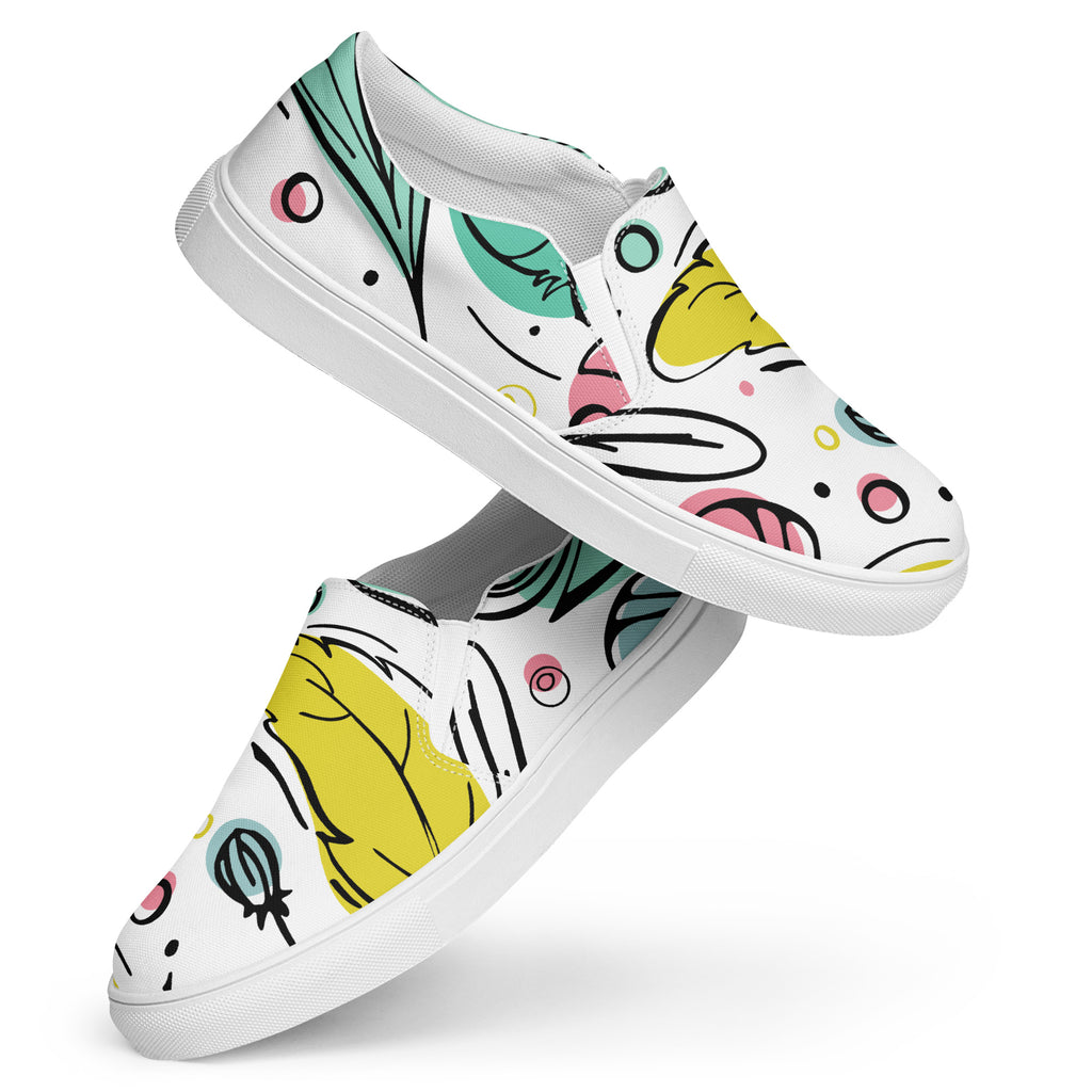 Ein Paar weiße Damen-Slip-on-Schuhe mit einem bunten, abstrakten Muster aus fließenden Formen in Gelb, Grün, Pink und Blau. Die Schuhe schweben vor einem weißen Hintergrund. Designed, by Just a Girl.