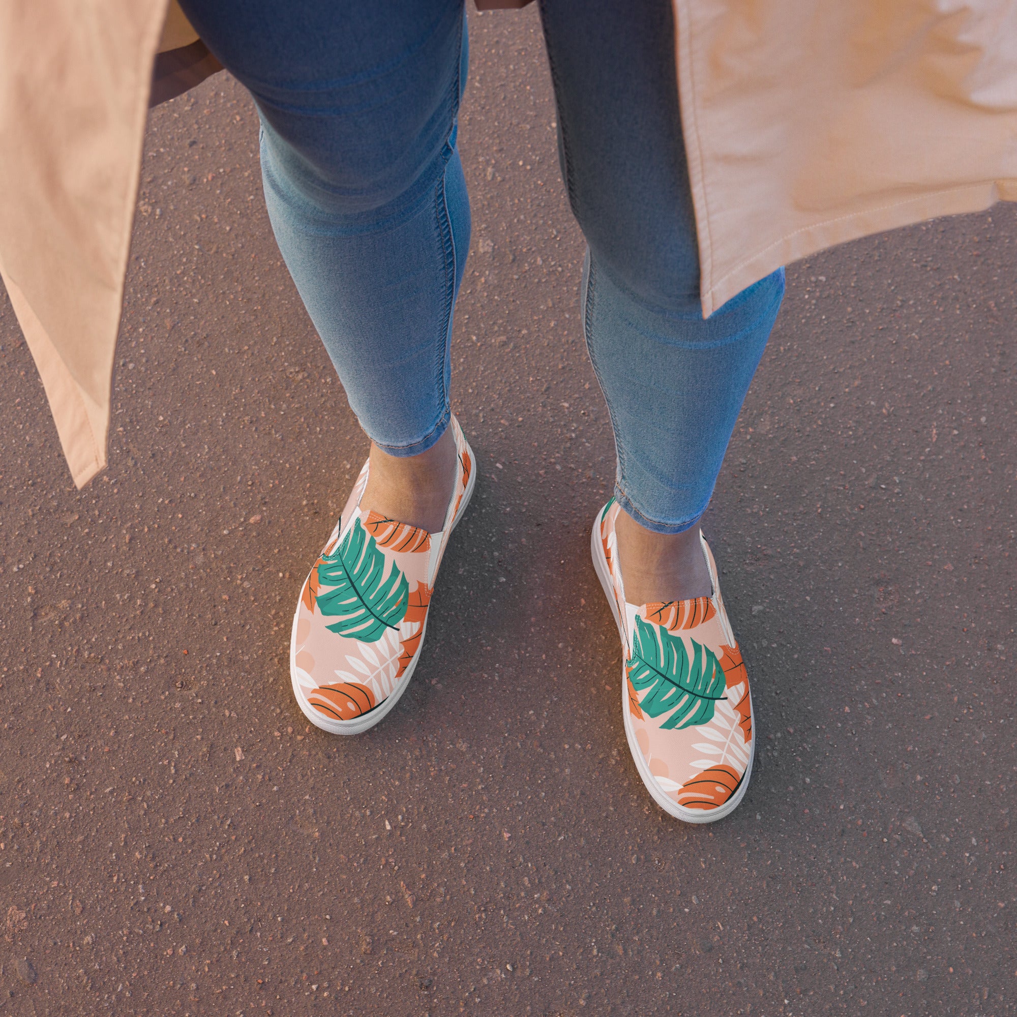 Ein weibliches Model zeigt tragend draßen die Slip Ons im Sitzen  mit einem Blättermuster in Grün, herbsltichen Orange und Weiß auf einem pastell farbenen orangen Hintergrund. Designed, by Just a Girl.