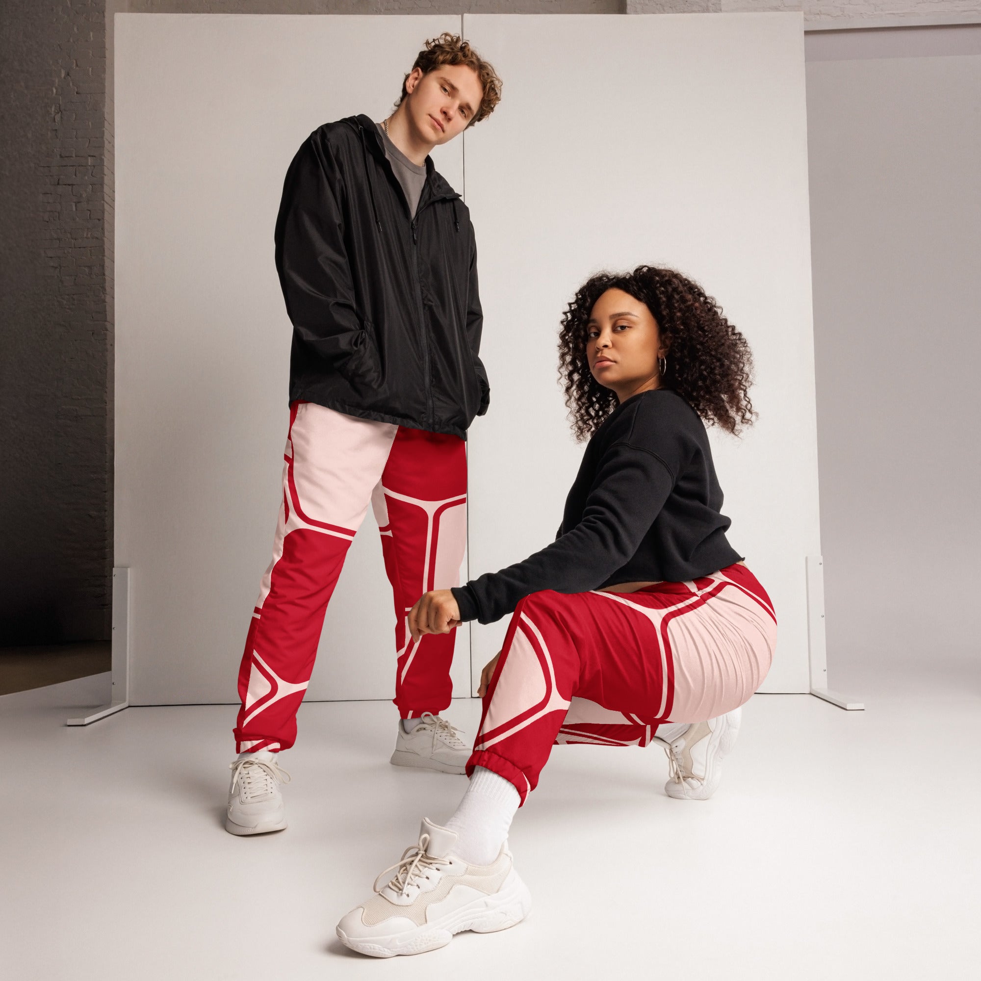 Damen Trainingshose in Rot und hellem Rosé mit einem abstrakten geometrischen Muster aus miteinander verbundenen, abgerundeten Rechtecken und Linien. Mockup Hosen Vorderansicht. Mockup Frau trägt Hose. By Just a Girl.