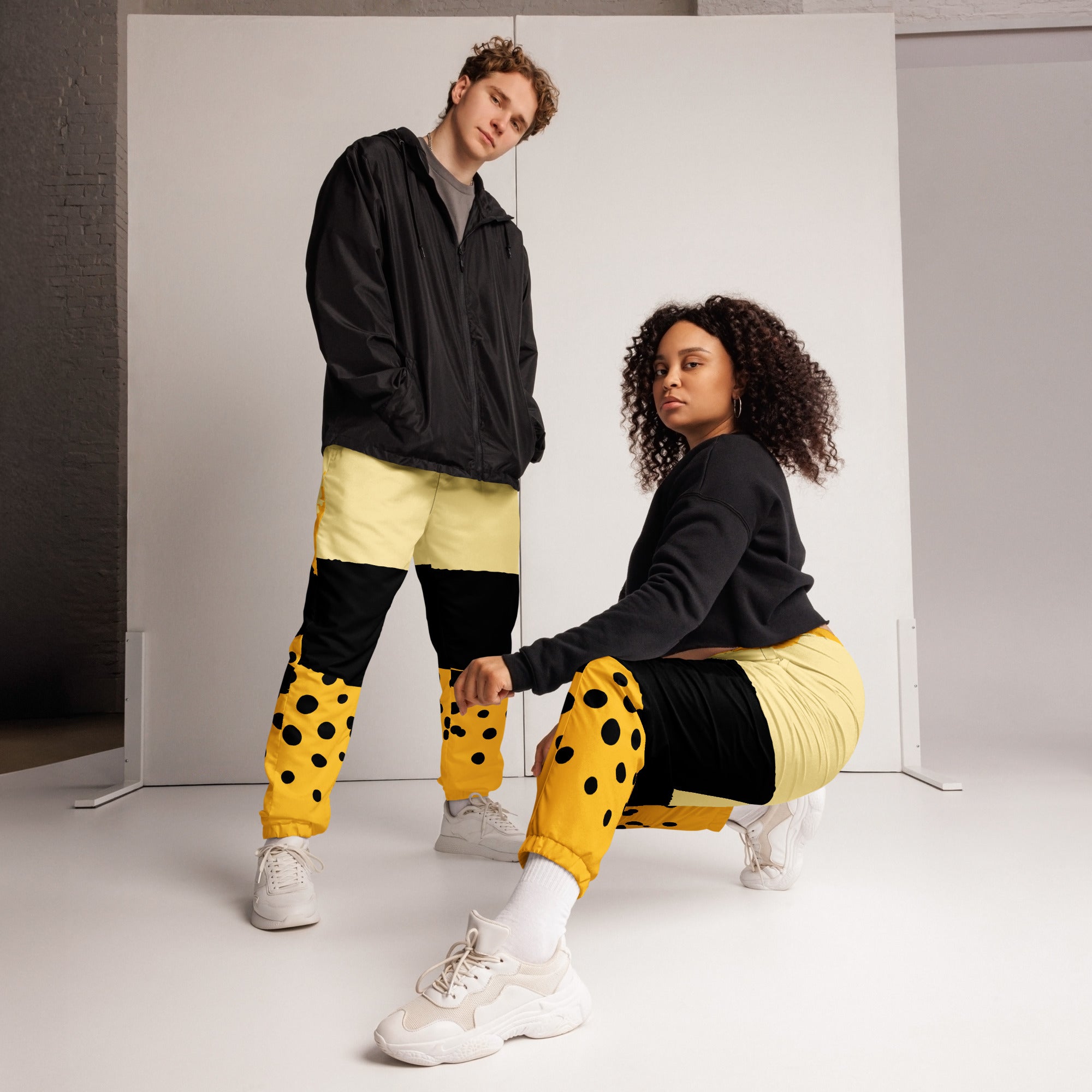 Damen Trainingshose in Gelb, Schwarz und einem pastell gelb, mit einem auffälligen schwarzen Punktemuster auf der unteren gelben Hälfte, mockup Frau trägt Hose. By Just a Girl.