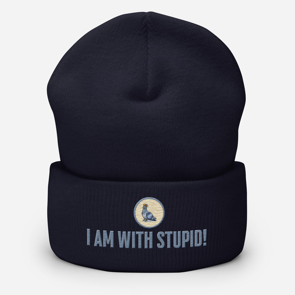 Eine dunkelblaue Cuffed Beanie mit aufgesticktem Patch als Taube mit einem runden beige-grauen Rahmen auf der Vorderseite. Darunter ein Schriftzug mit Grossgeschriebenen Buchstaben "I Am with Stupid!" Designed, by Just a Girl.
