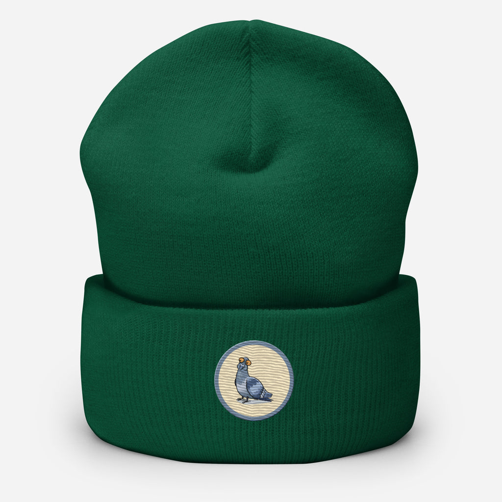 Eine Fichtengrüne Cuffed Beanie mit aufgestckter Taube in einem grau-beigen rundem Rahmen auf der Vorderseite. Designed, by Just a Girl.