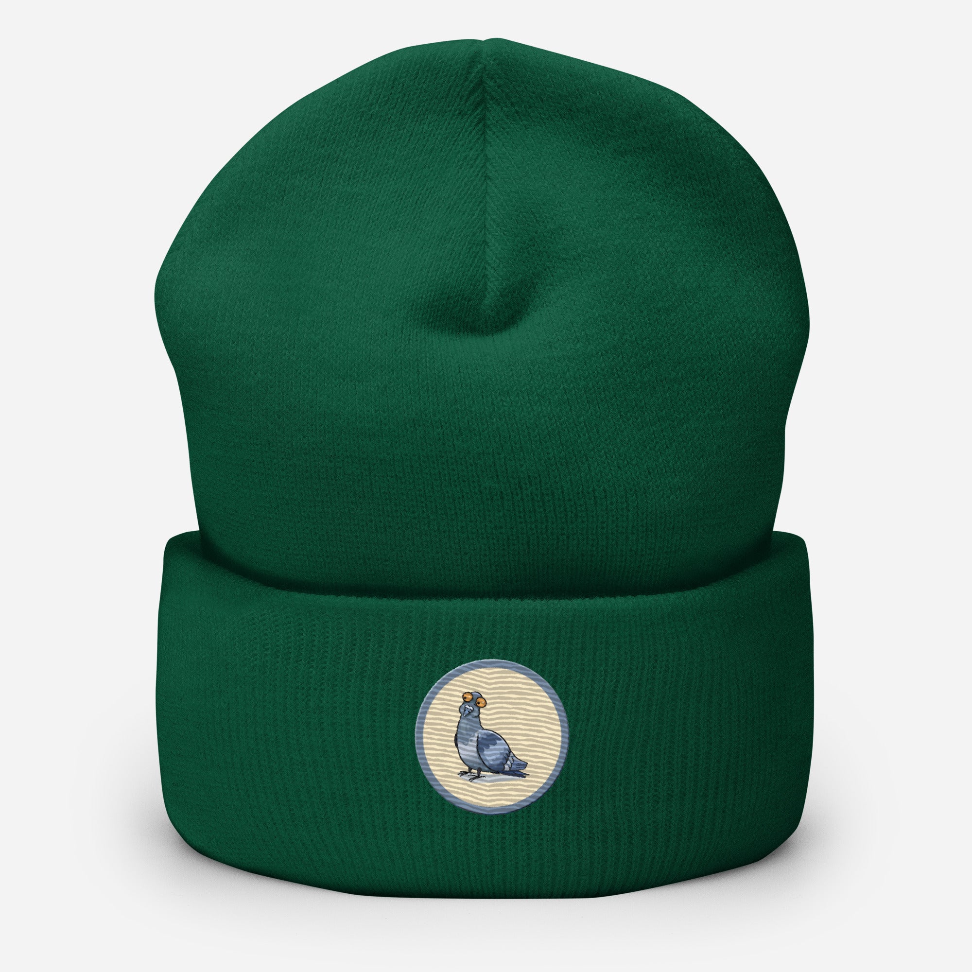 Eine Fichtengrüne Cuffed Beanie mit aufgestckter Taube in einem grau-beigen rundem Rahmen auf der Vorderseite. Designed, by Just a Girl.