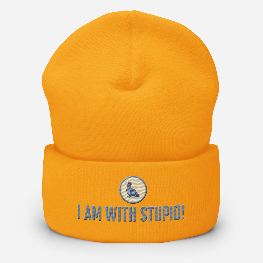 Eine gold-gelbe Cuffed Beanie mit aufgesticktem Patch als Taube mit einem runden beige-grauen Rahmen auf der Vorderseite. Darunter ein Schriftzug mit Grossgeschriebenen Buchstaben "I Am with Stupid!" Designed, by Just a Girl.